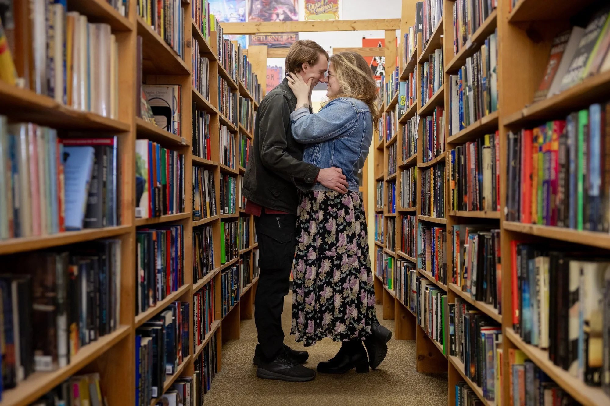 Couple kissing between shelves during a bookstore engagement session