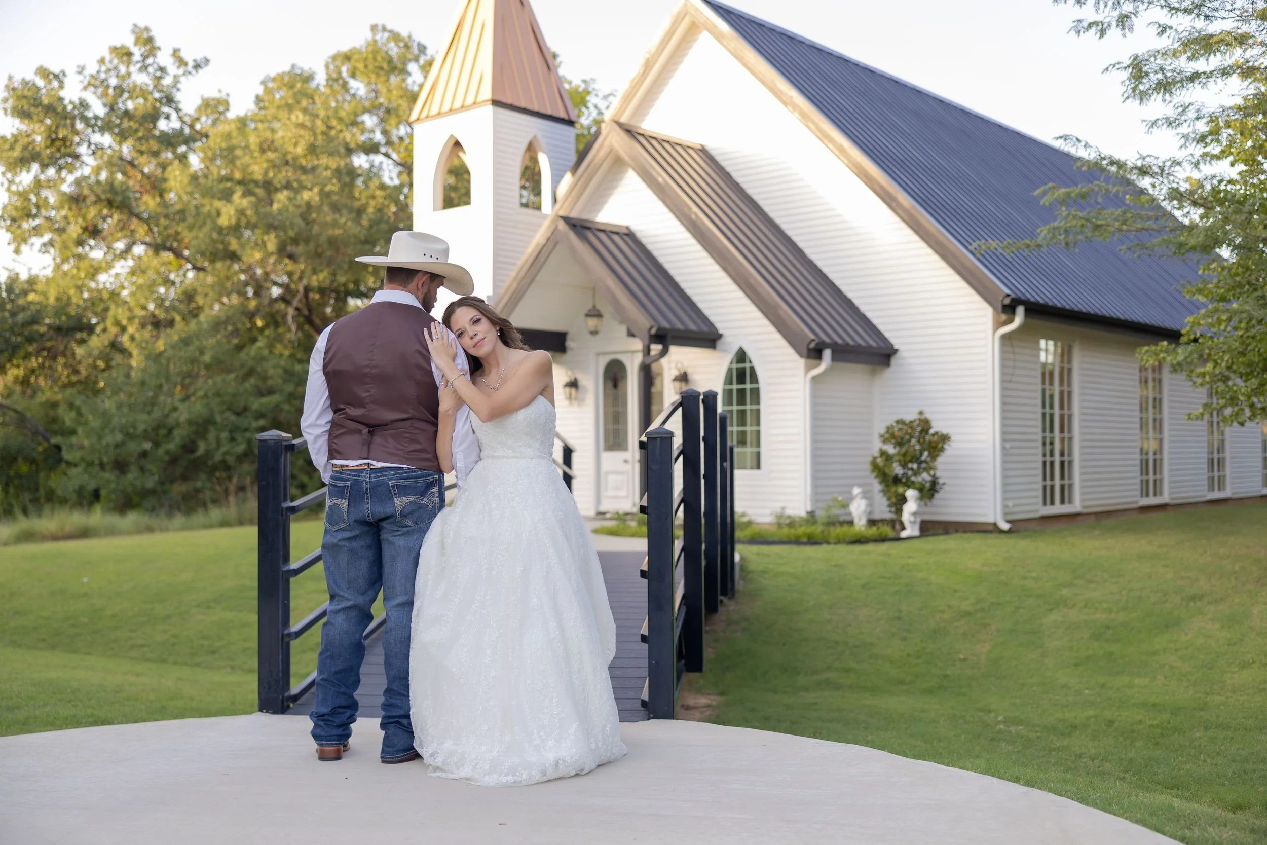 Heather and Geffrey in front of the white chapel at The Barn at Paradise Place in Weatherford, TX