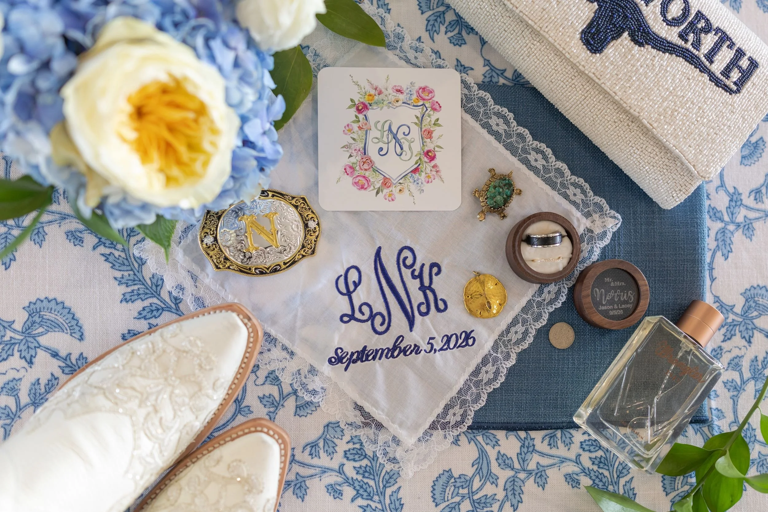 Blue and white wedding invitation flat lay with rings and details for Lacey and Jason