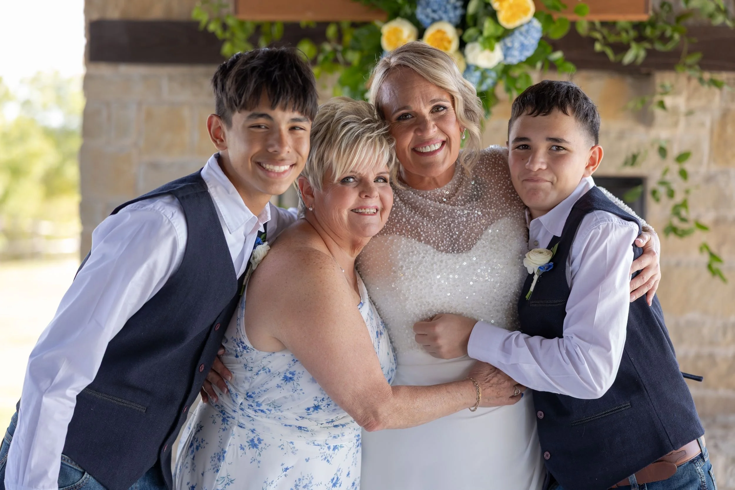 Bride hugging two young groomsmen during family photos at Dove Ridge Vineyard