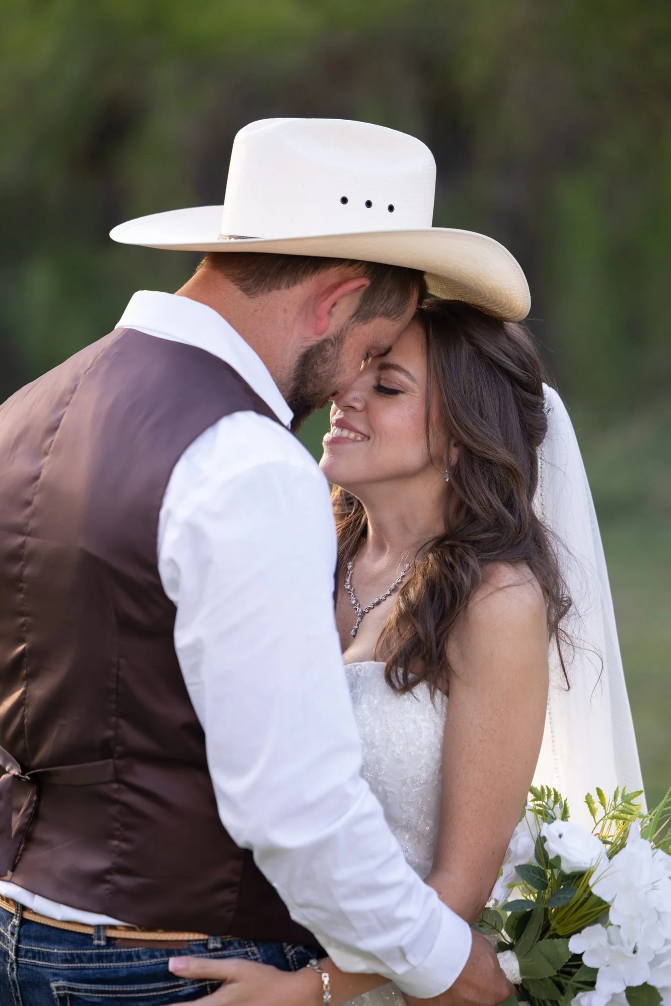 Romantic portrait of a cowboy groom in a white hat with his bride at a Texas wedding
