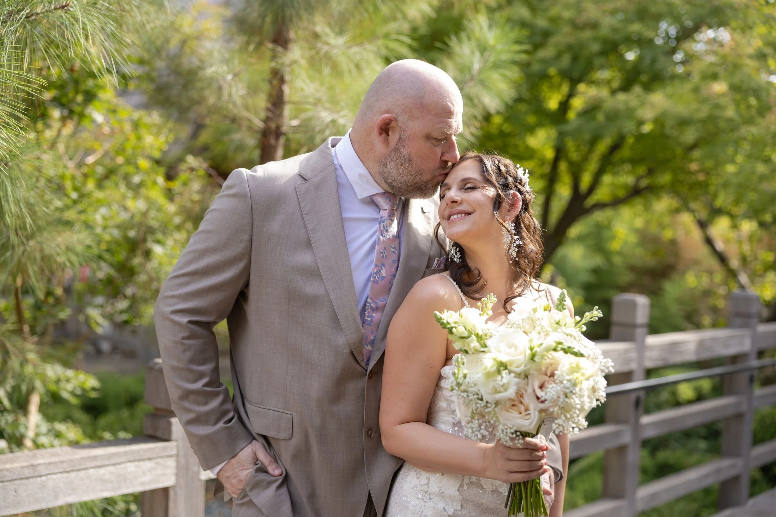 Bride and groom cheek to cheek on a garden bridge during Fort Worth wedding portraits