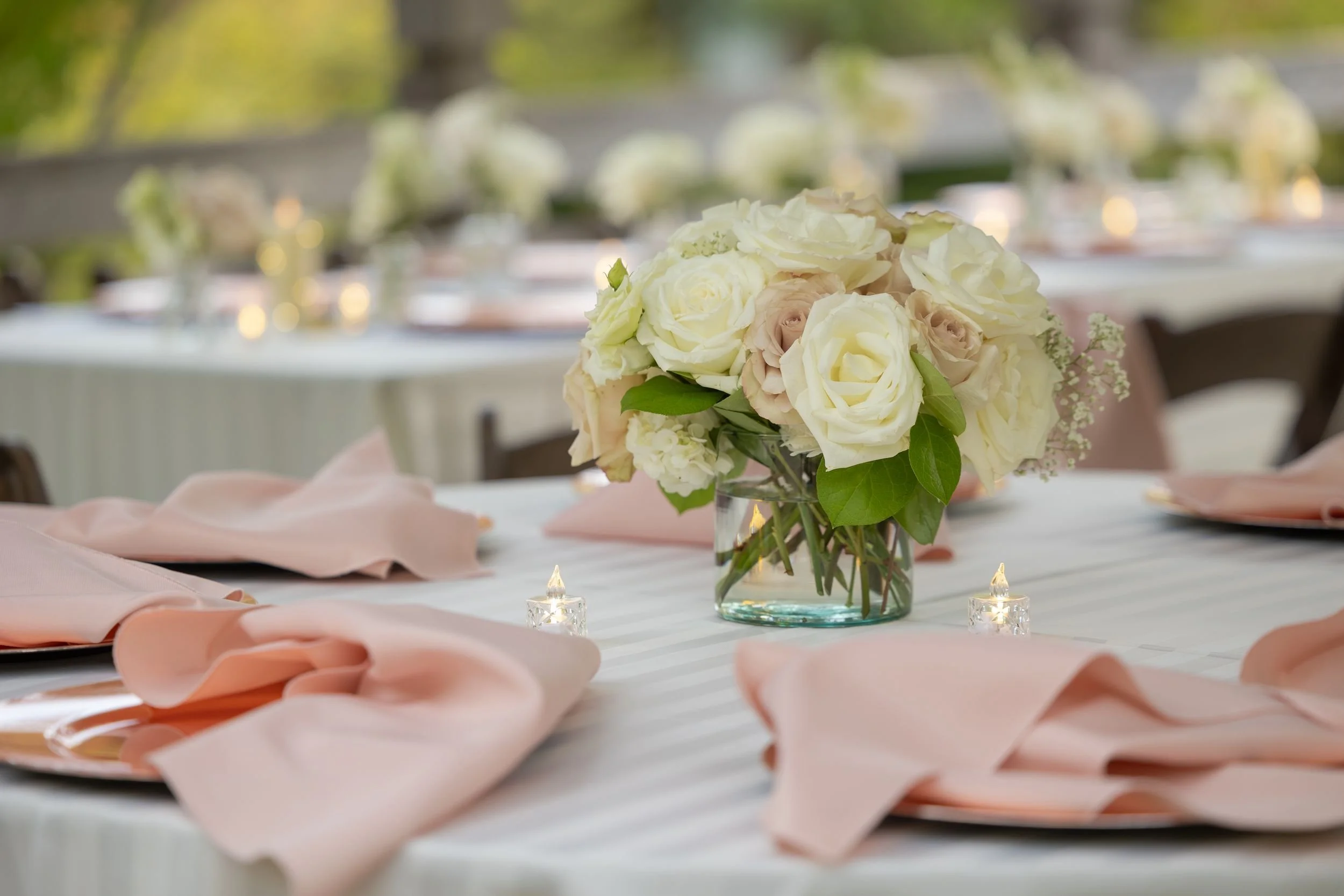 Reception table with blush napkins and a white floral centerpiece at a Fort Worth garden wedding
