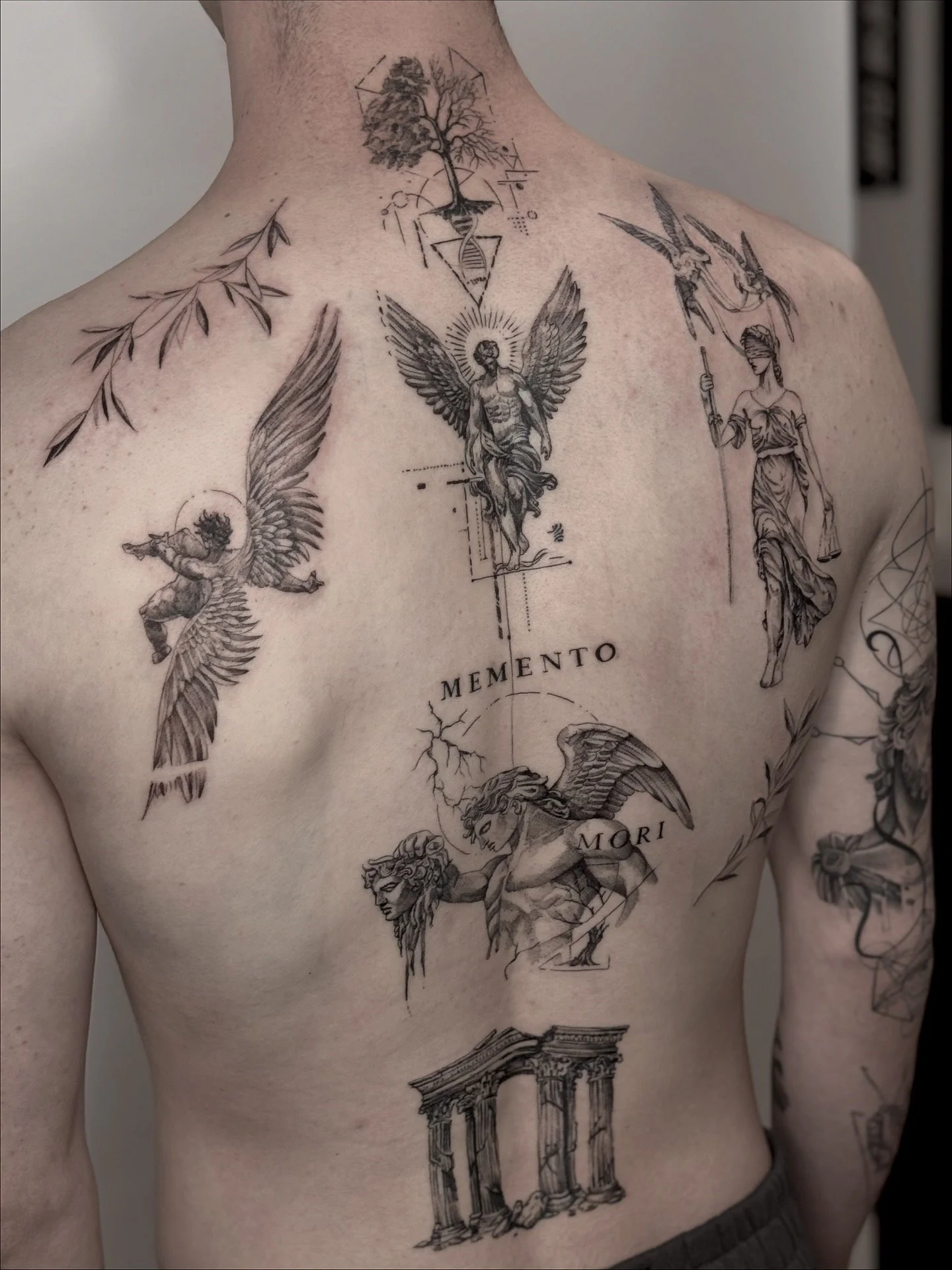 Fine-line tattoo in Paris. Black and gray tattoo on person's back featuring a tree, mythological figures, birds, and architectural elements with Latin words.