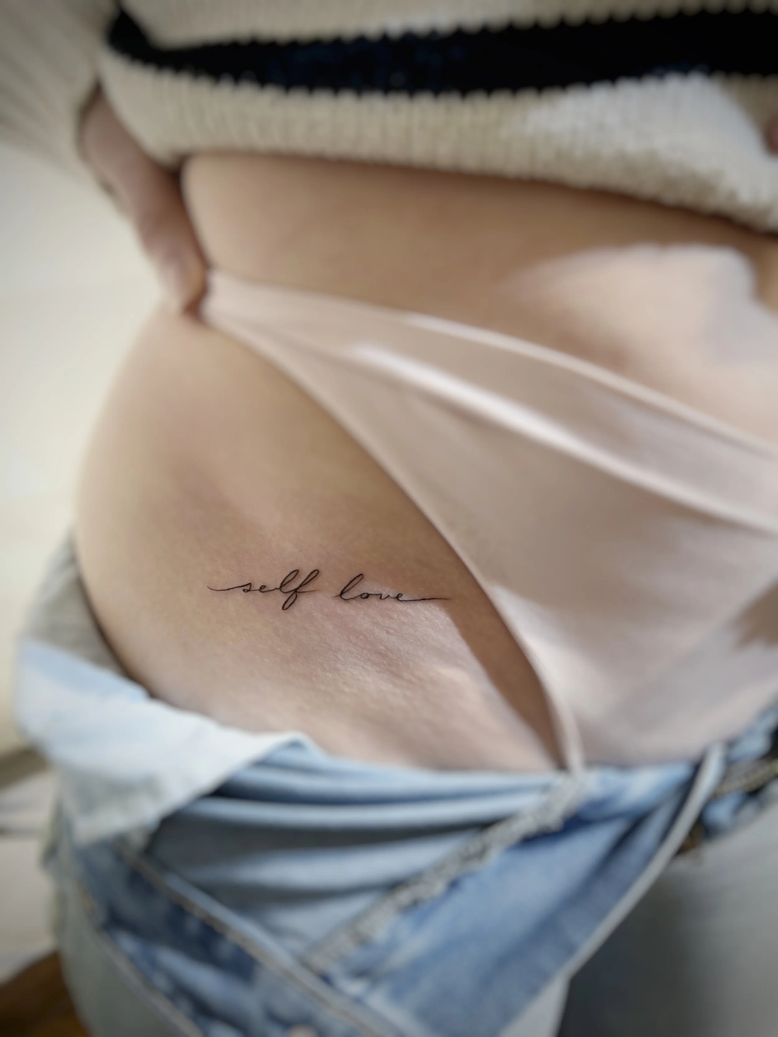 Close-up og elegant script fine-line tattooed on the skin. Fine line tattooing, delicate lines, thoughtful detail and a sense of lightness. From botanical drawings and subtle symbols to more intricate compositions.