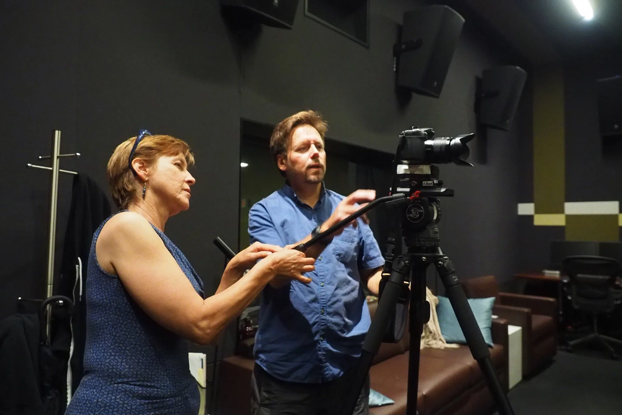 Patrushkha and a man working with a professional video camera on a tripod in a studio.