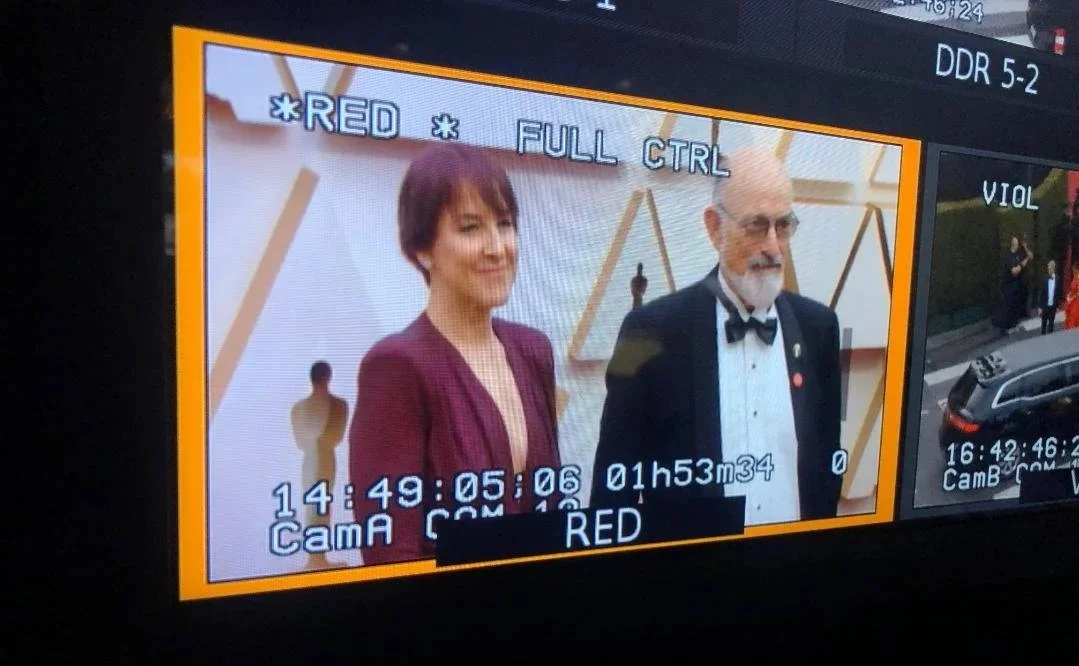 Patrushkha and Mark on the Oscars red carpet in a maroon dress and a in a tuxedo with a bow tie.