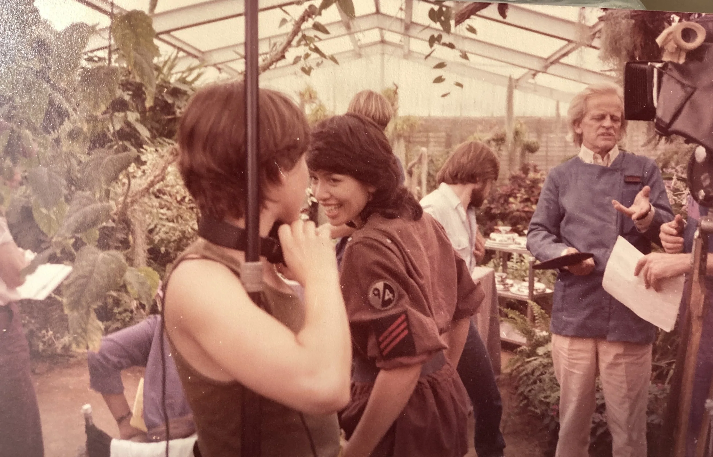 People chatting and smiling on set of a film, holding audio equipment.