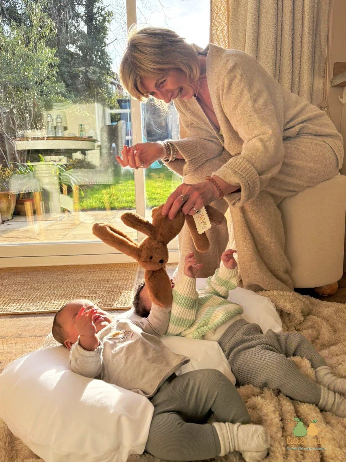 Adult interacting with a baby supported on a pillow during playtime at home.