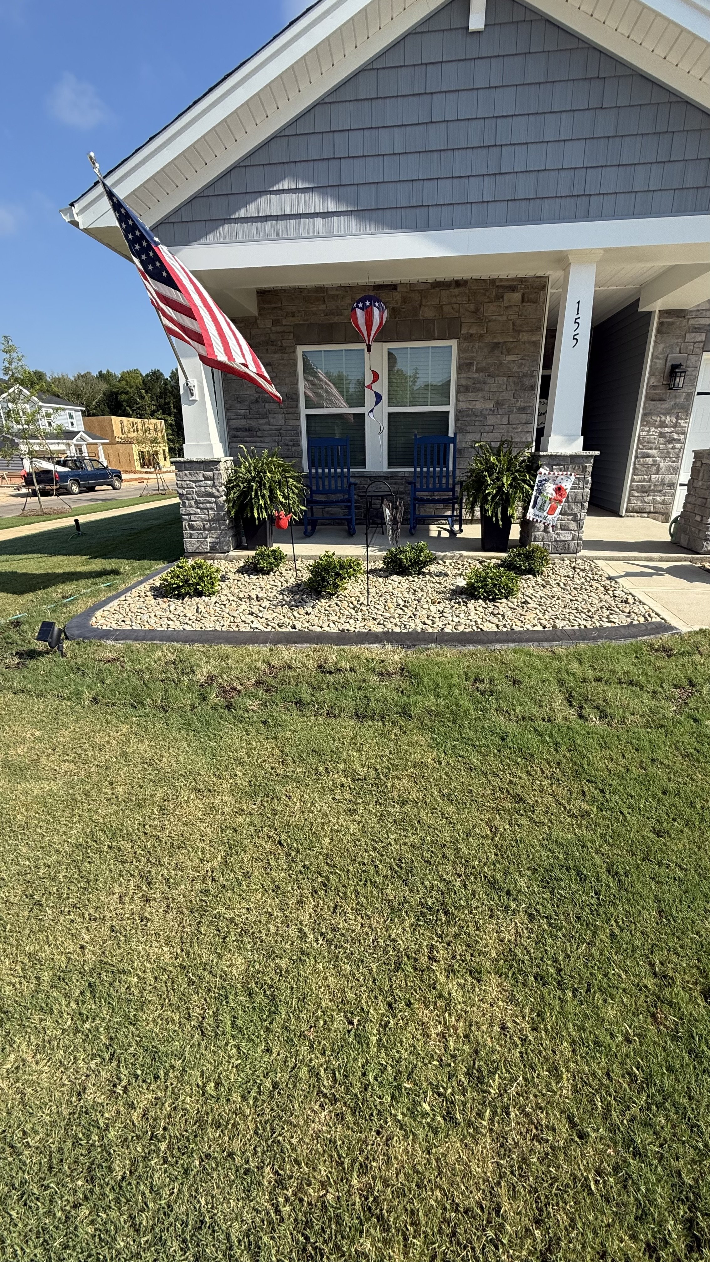 Front porch with stamped concrete edging, river rock, and potted plants.