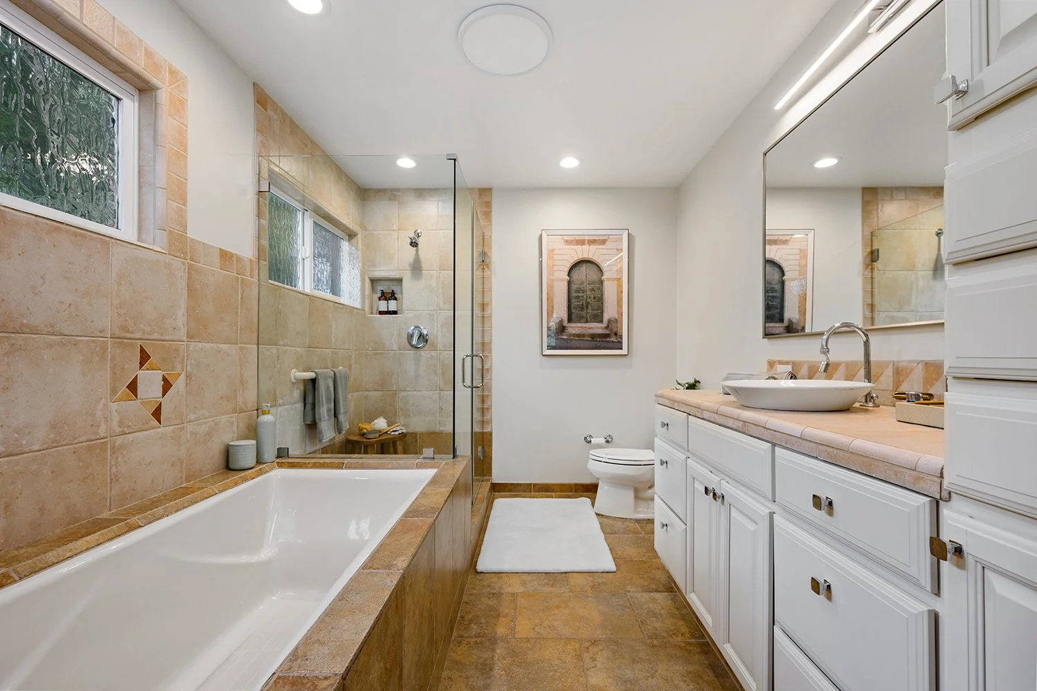 Bathroom with a bathtub, walk-in shower, toilet, and a vanity with a large mirror.