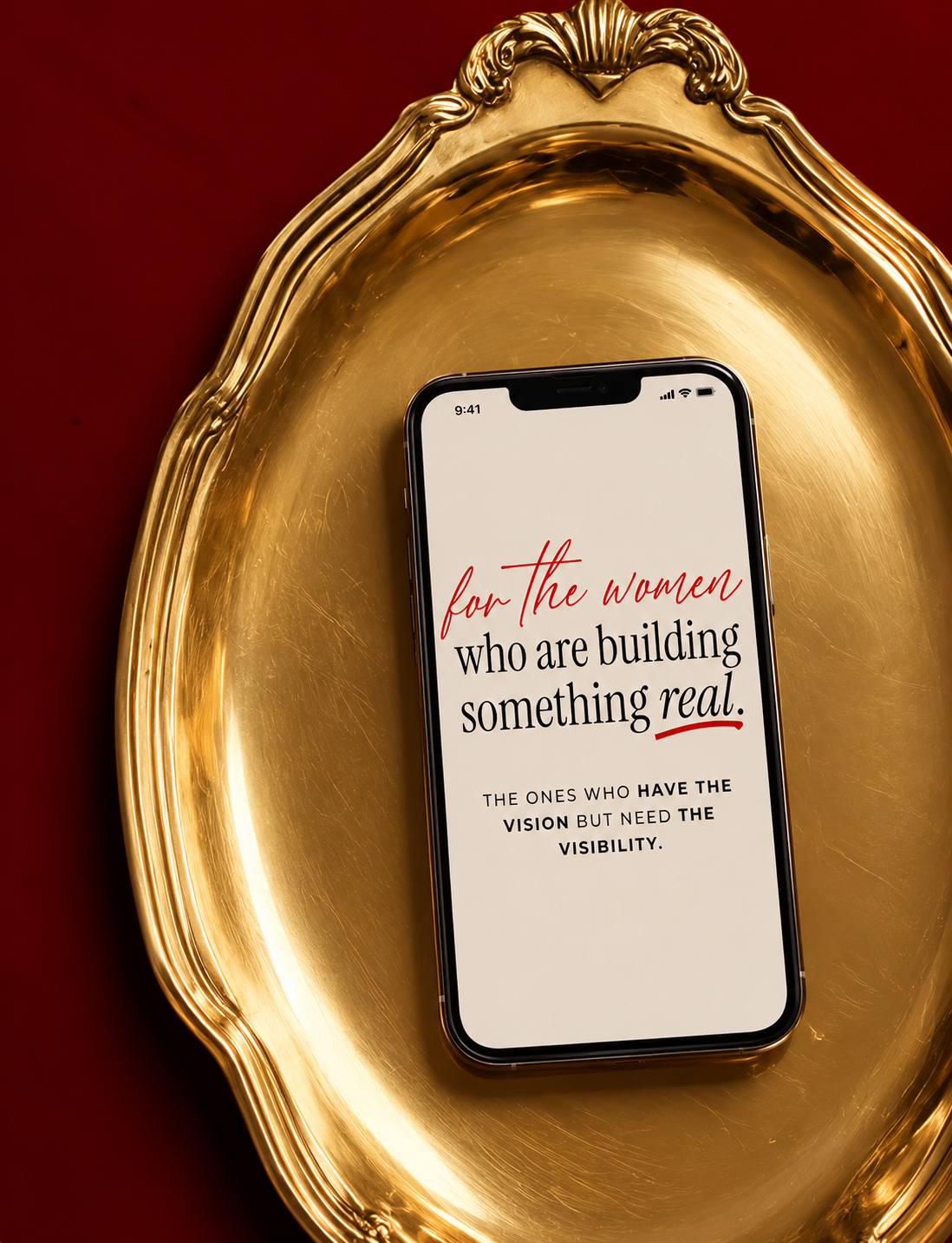 Smartphone displaying text on a white background, placed on a gold decorative tray with a deep red surface underneath.
