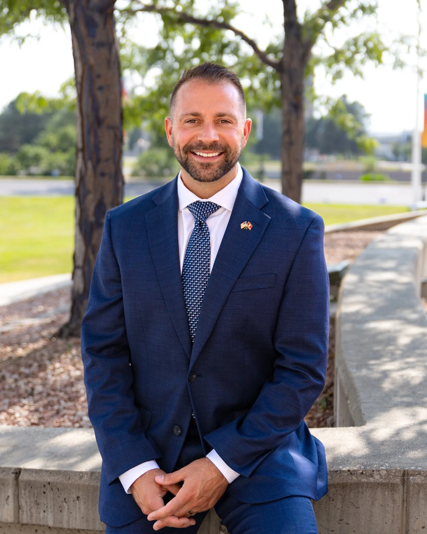 Travis Marschner, Castle Rock, CO real estate agent and Marine Corps veteran, smiling outdoors in a navy suit