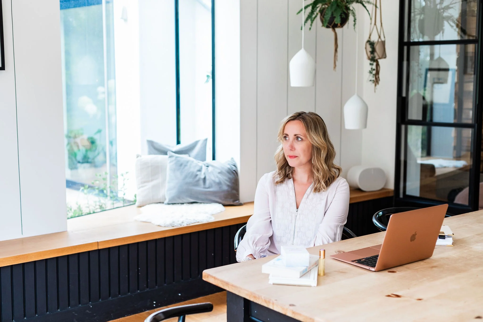 Lee-Anne Burgess working at her laptop in a bright workspace.