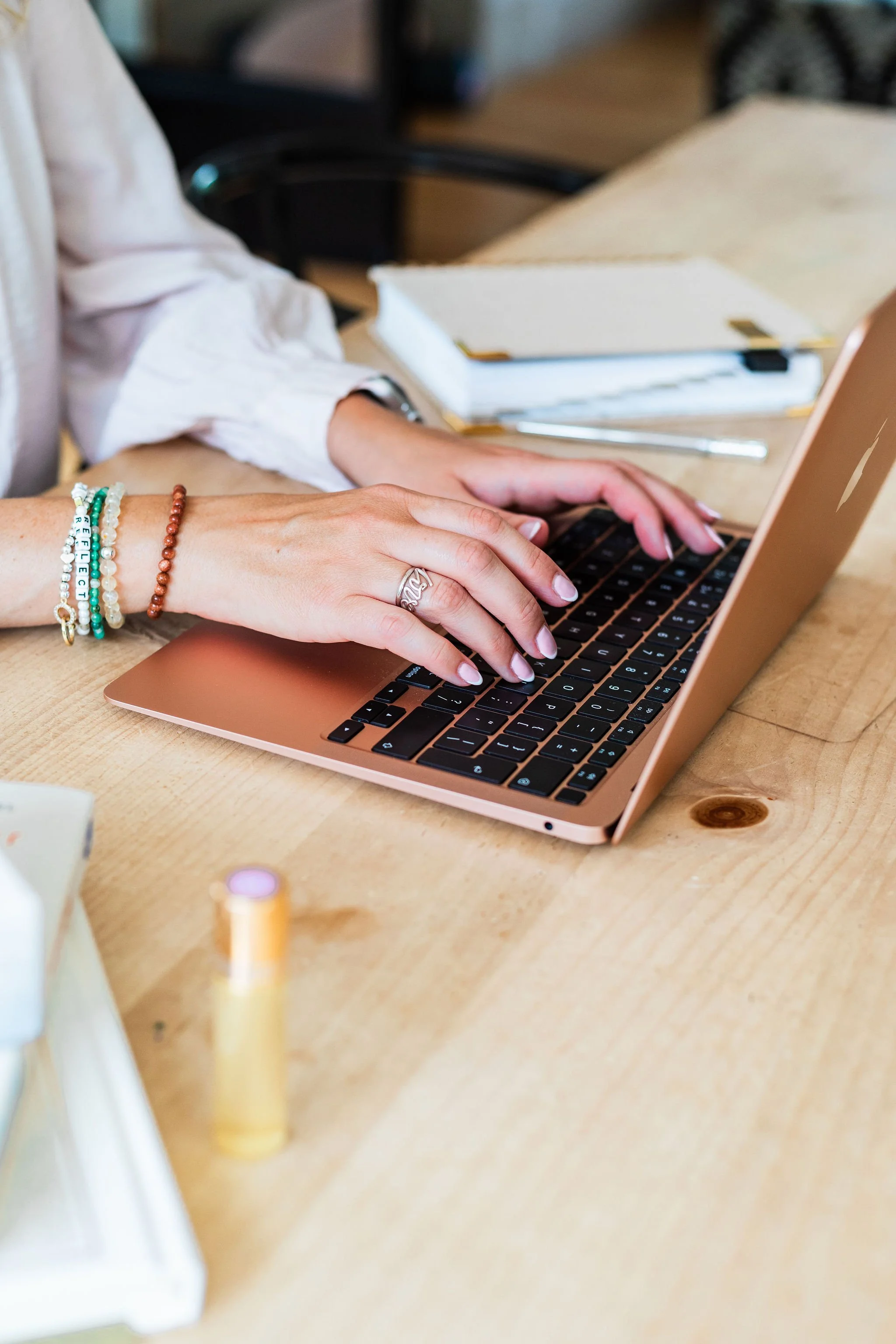 Close-up of Lee-Anne Burgess typing on a laptop beside a notebook.