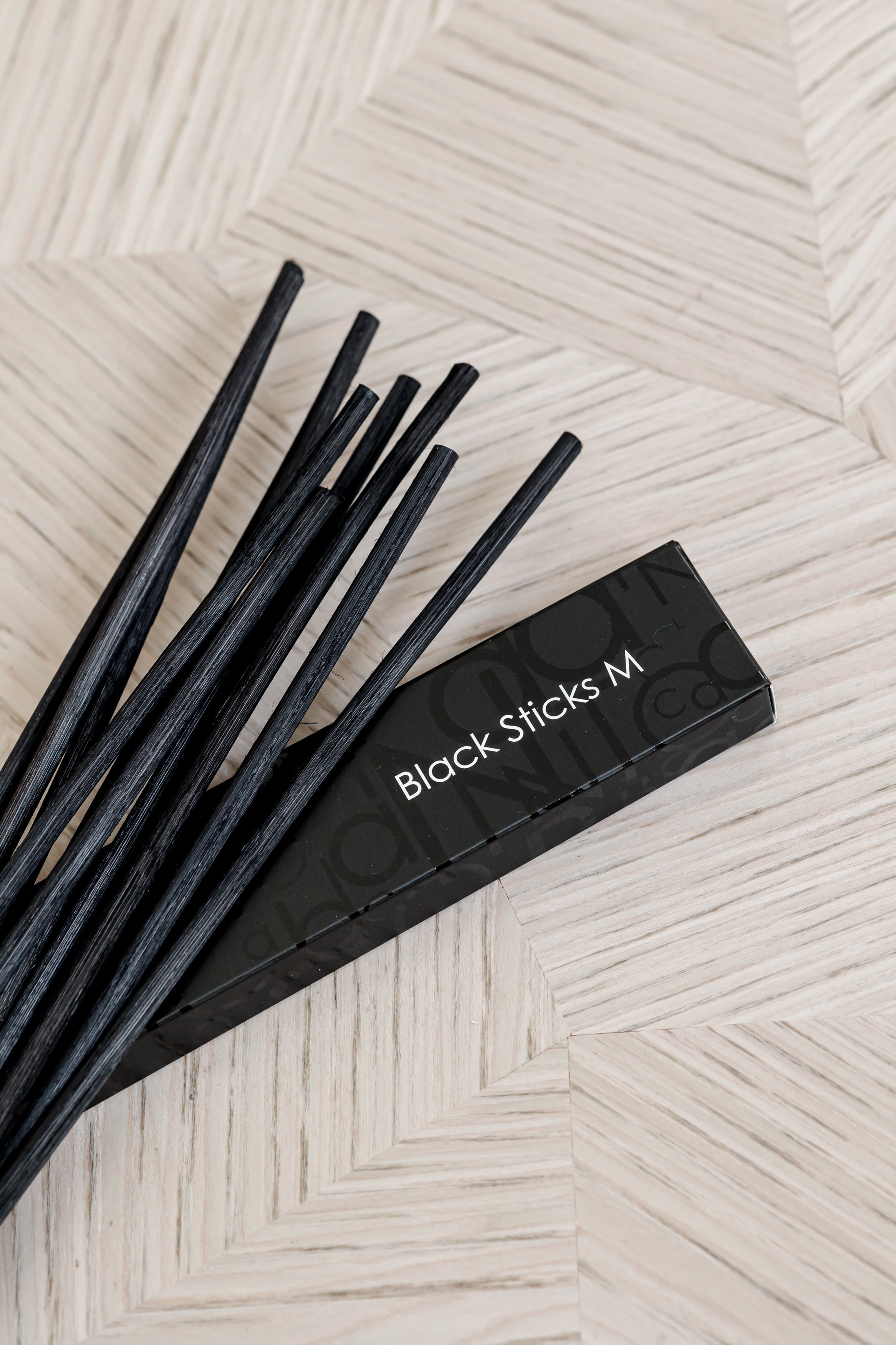Baobab Collection black diffuser sticks fanned out beside their box