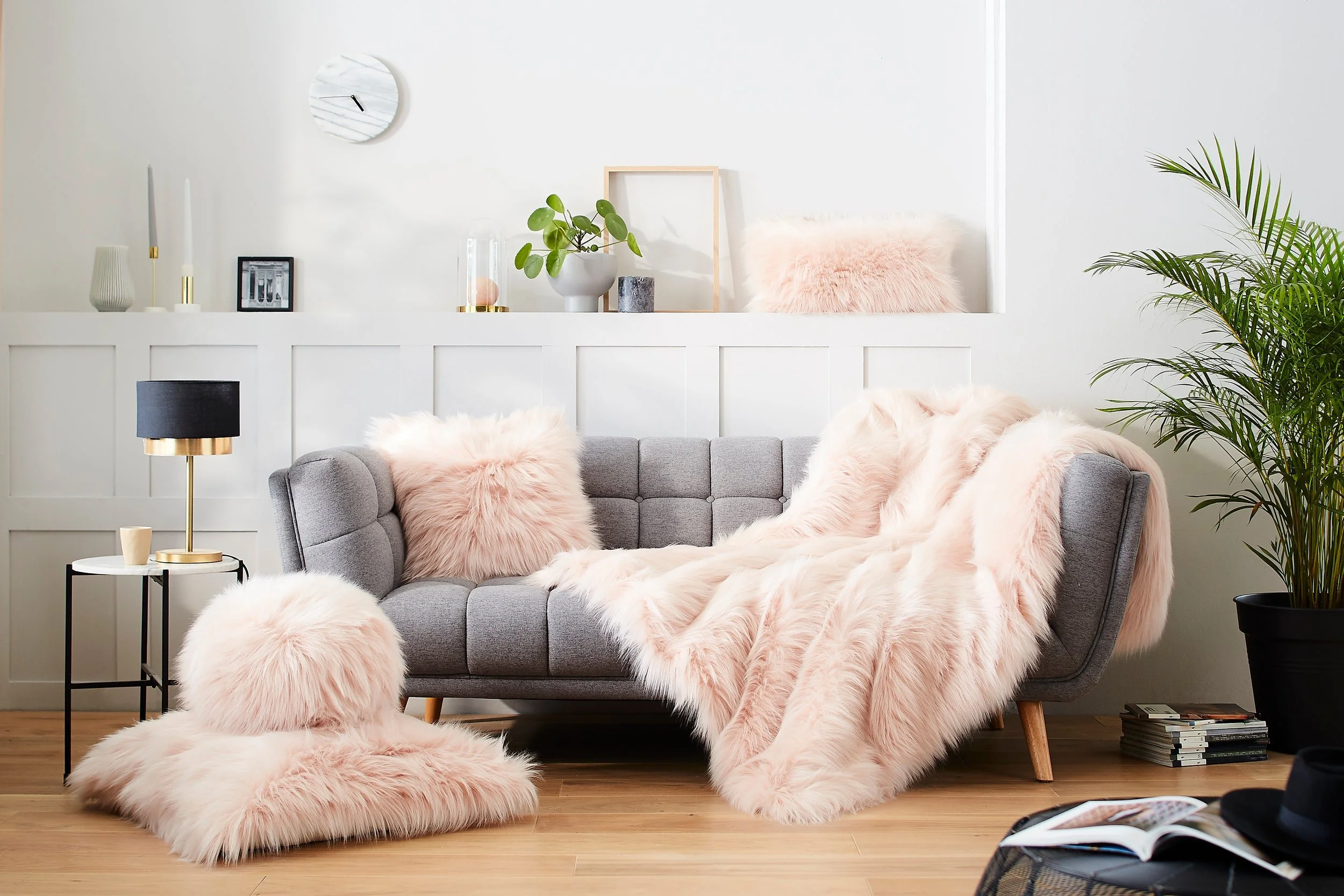 Evelyne Prélonge faux fur throw and cushions in blush on a grey sofa in a bright living room