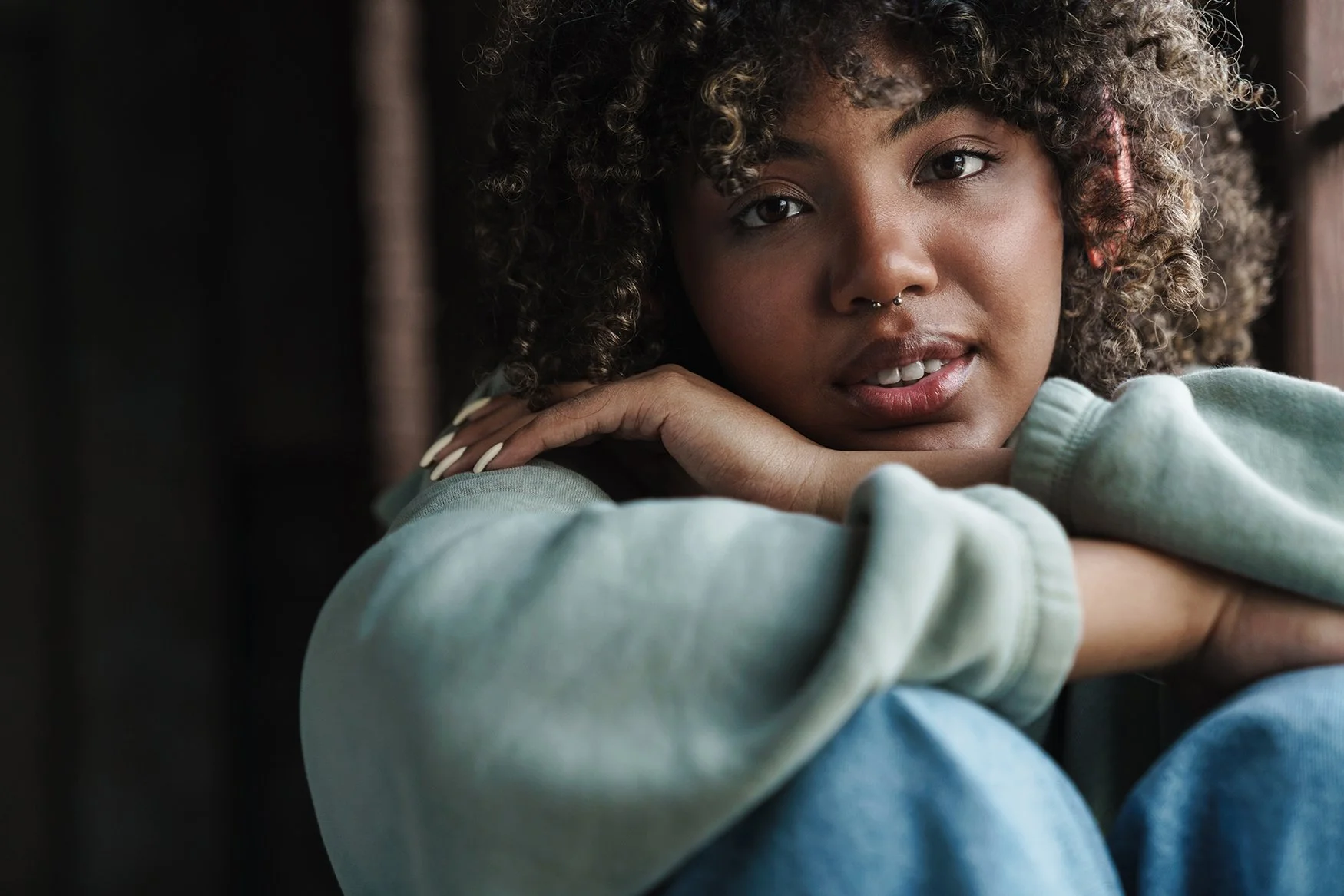 Sad young woman sitting on floor leaning on her arms