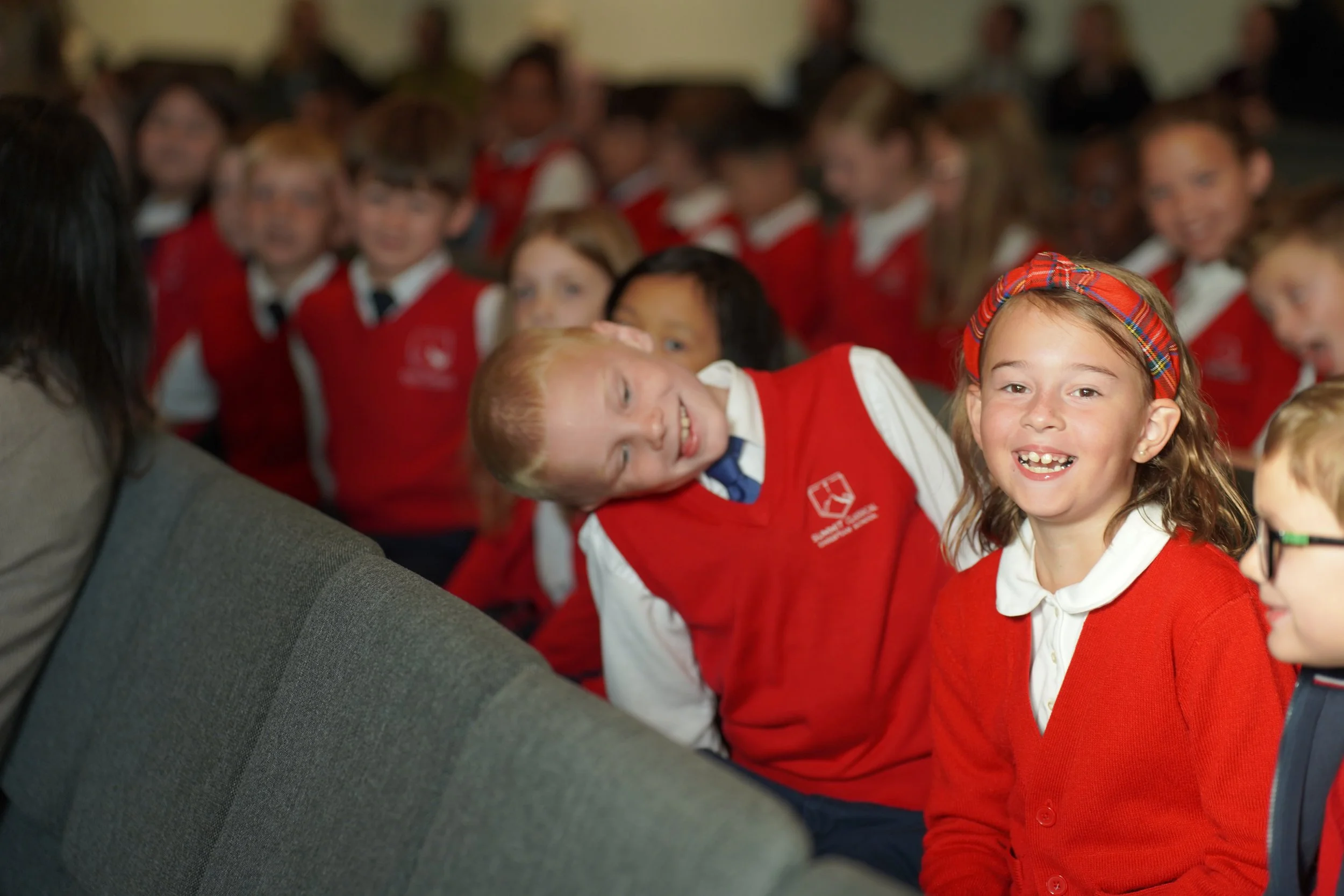 Smiling elementary school children in red uniforms gathered for a group photo