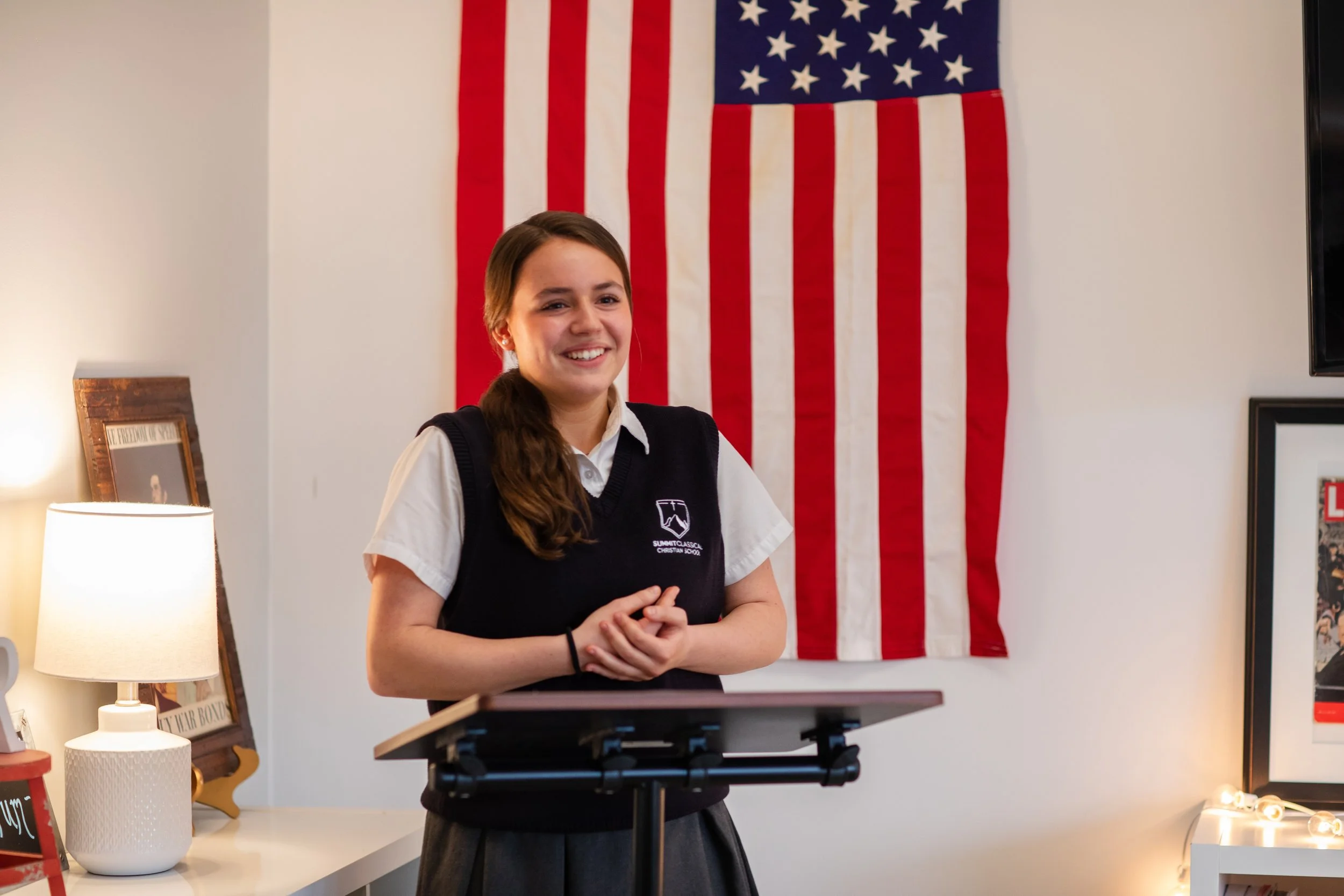 Upper School student smiling at a podium during a class presentation