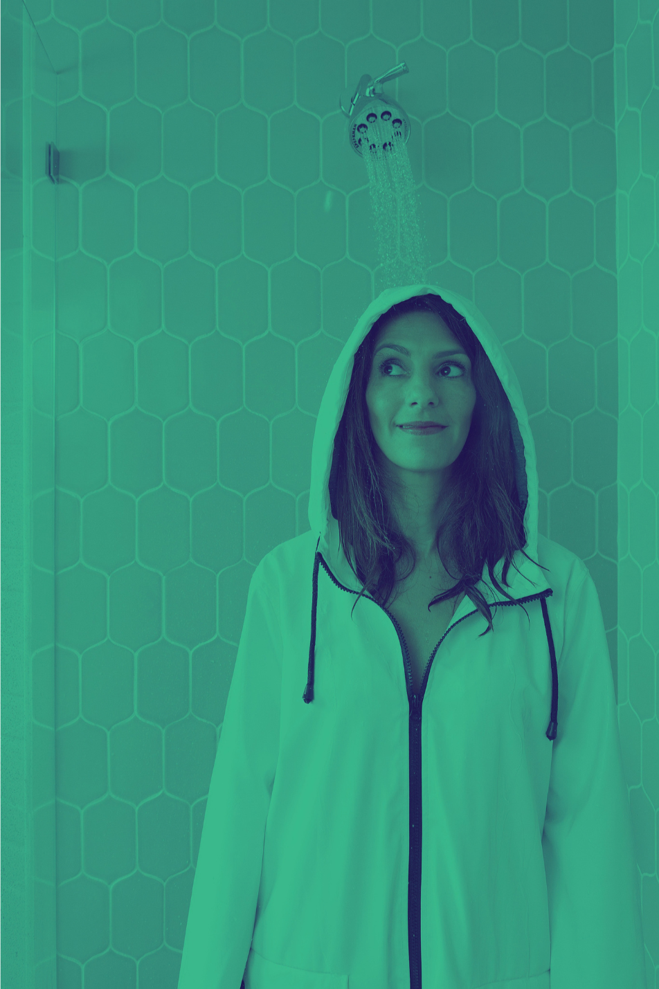 Clara Bijl with dark hair wearing a white hoodie standing under a shower in a tiled bathroom.