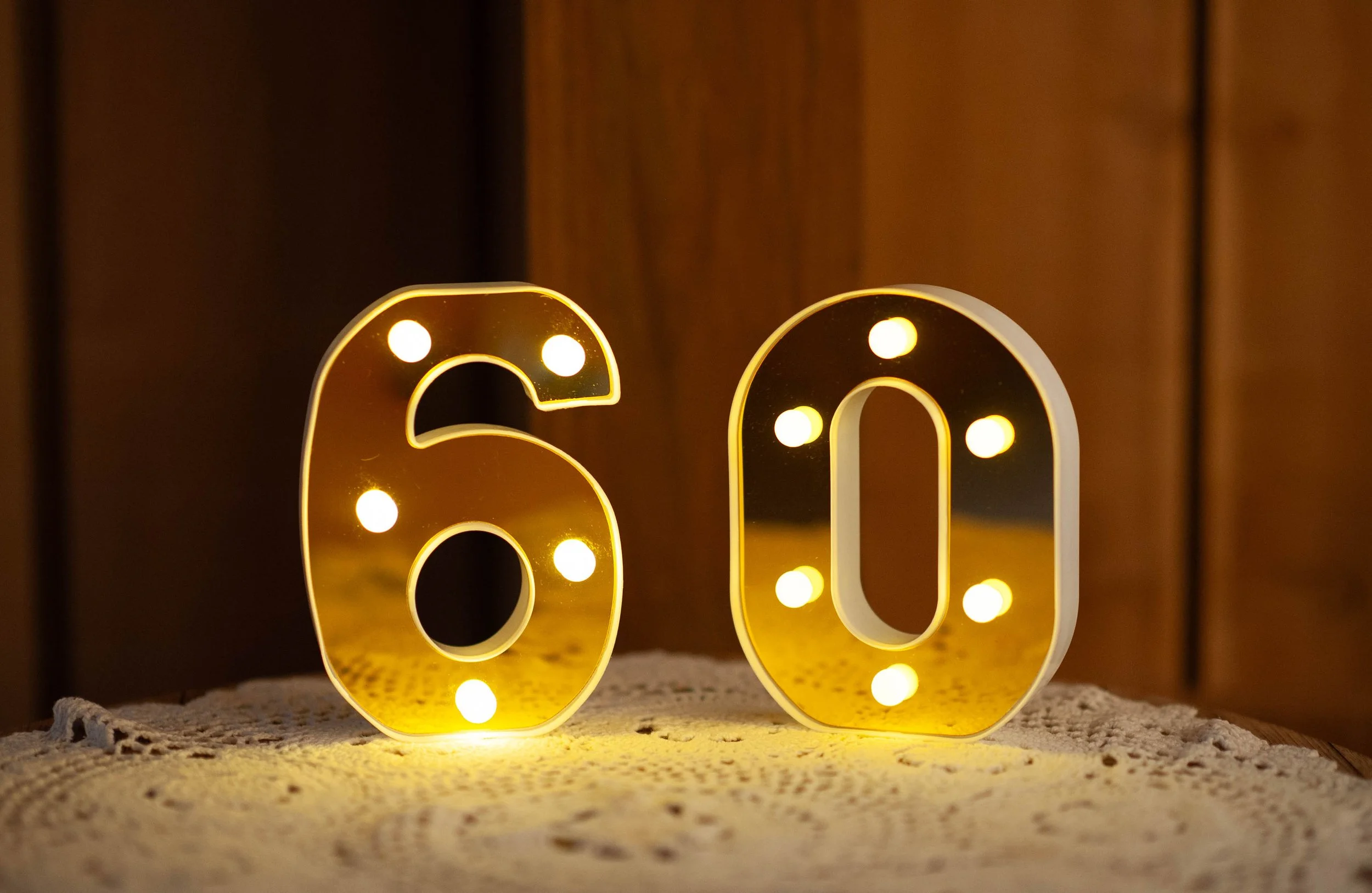 Illuminated 60 display with warm LED lights for an elegant milestone birthday celebration.
