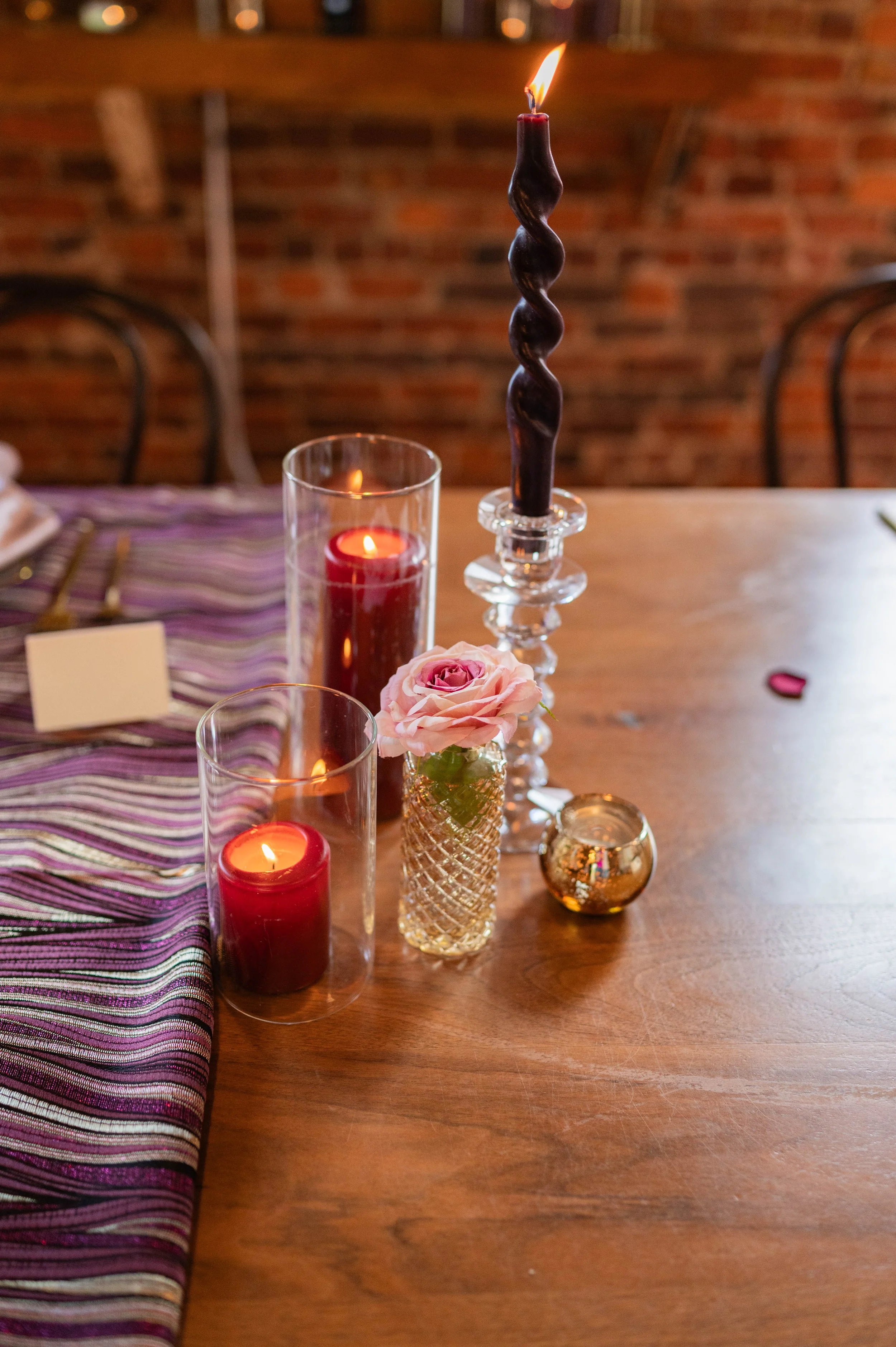 Romantic candlelight styling with black taper candle, burgundy votives and soft floral details.