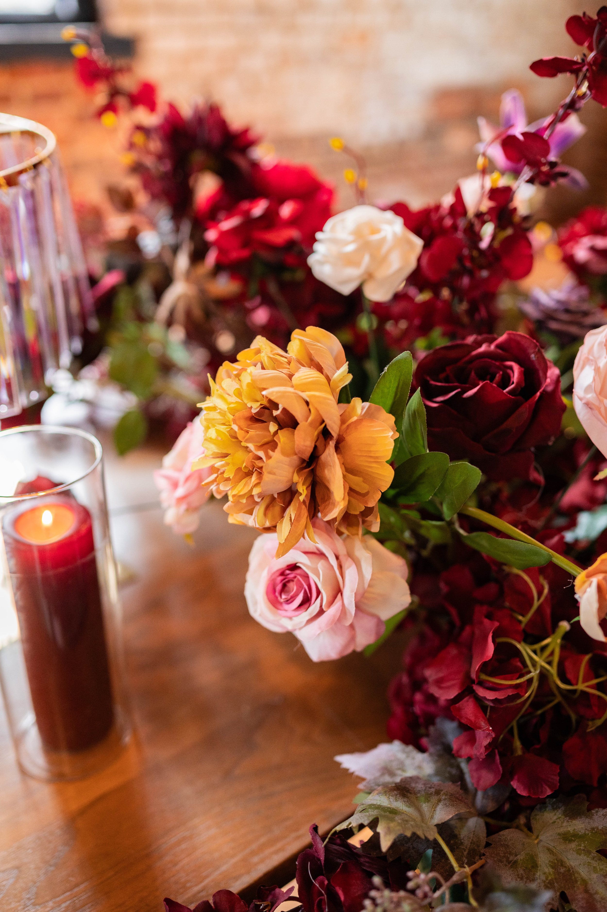 Lush burgundy and blush floral arrangement with warm candlelight.