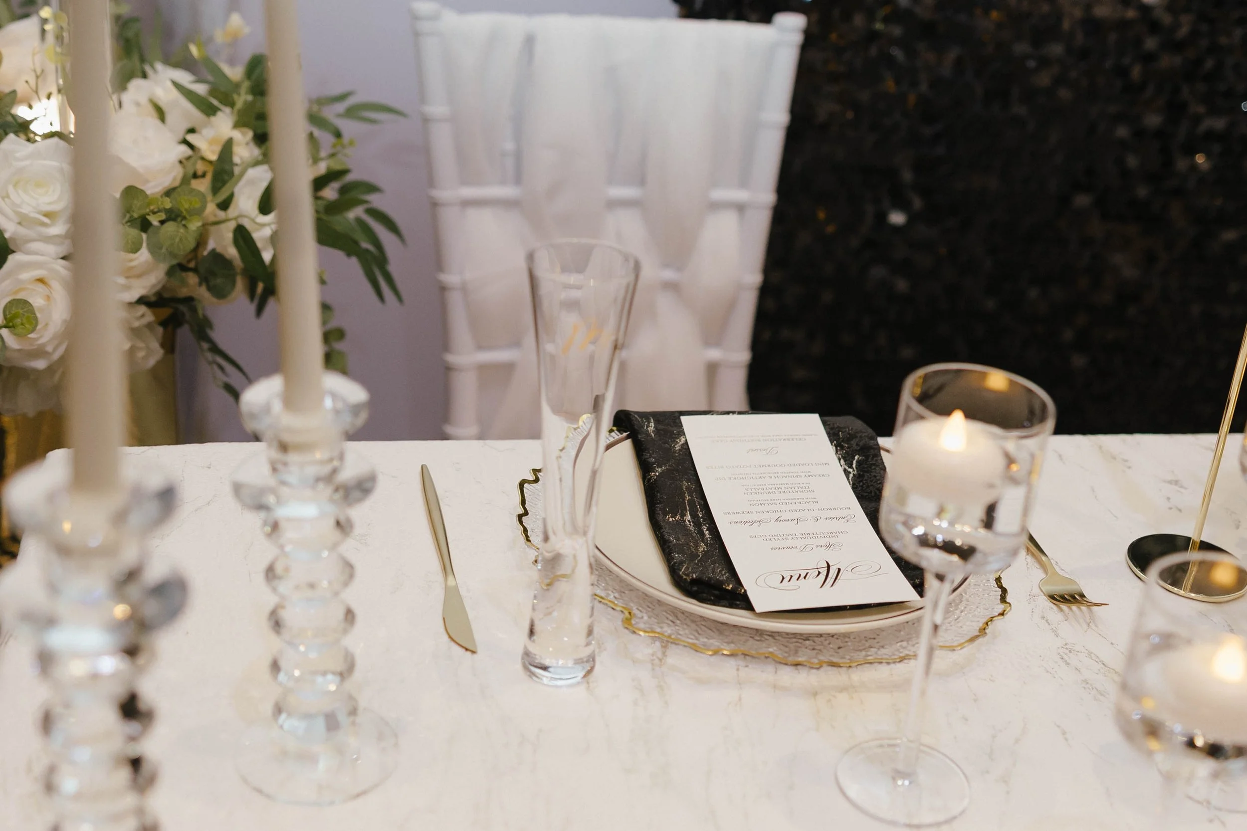 Black and white sweetheart table setting with crystal candlesticks and gold details.