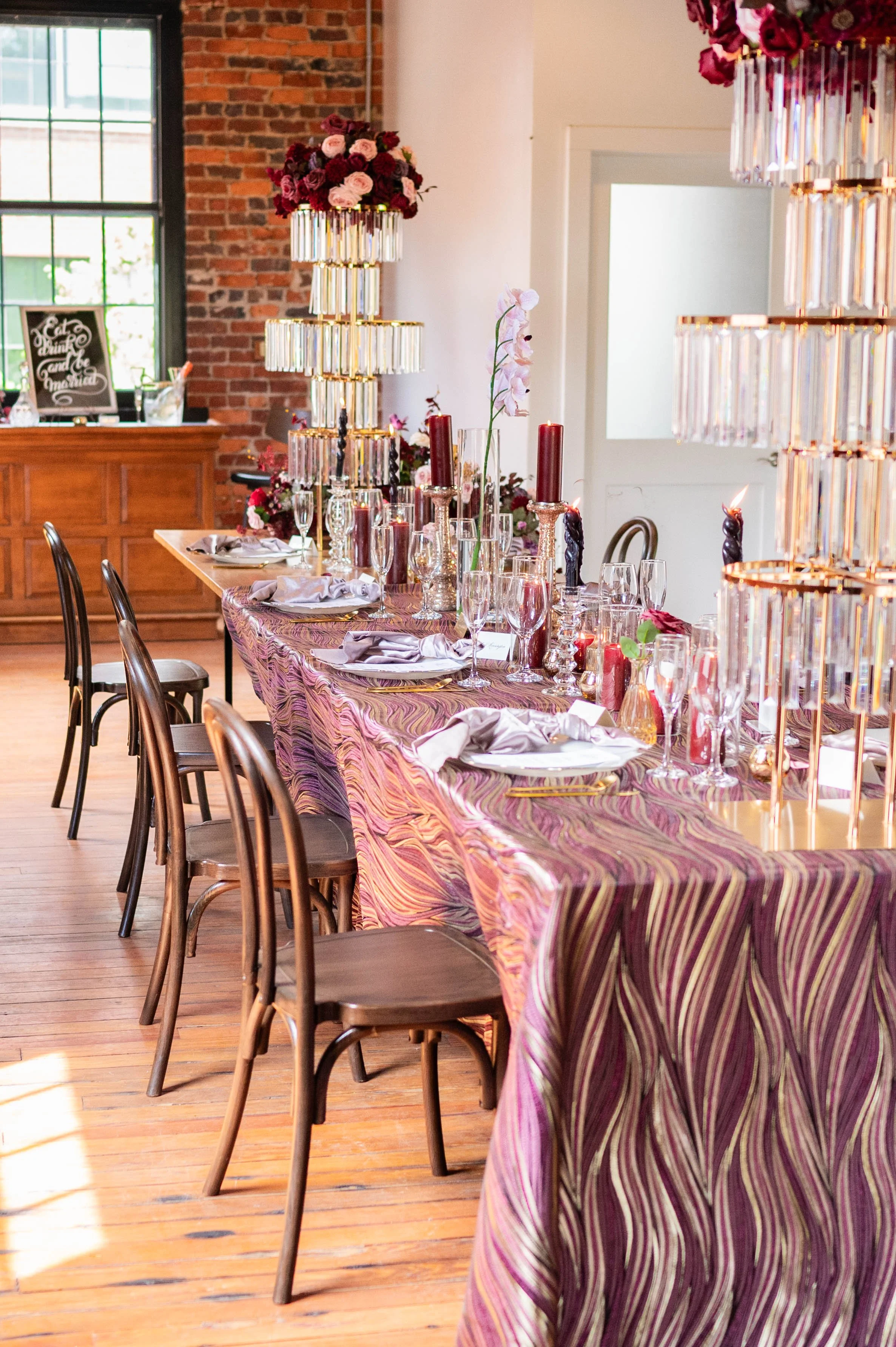 Layered reception tablescape with statement crystal centerpieces and rich burgundy accents.
