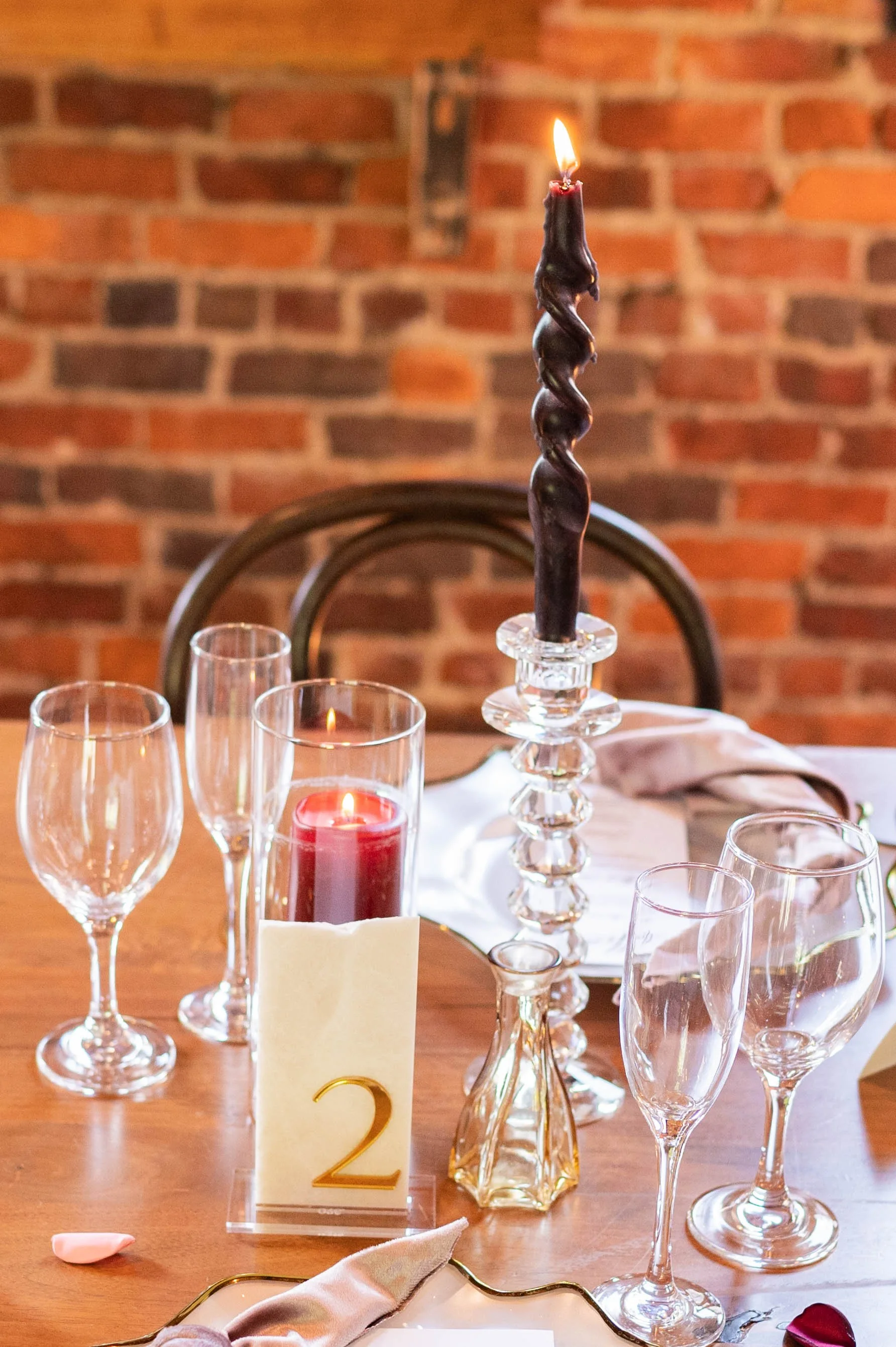 Black twisted taper candle with burgundy candlelight and crystal accents on an elegant wedding tablescape.