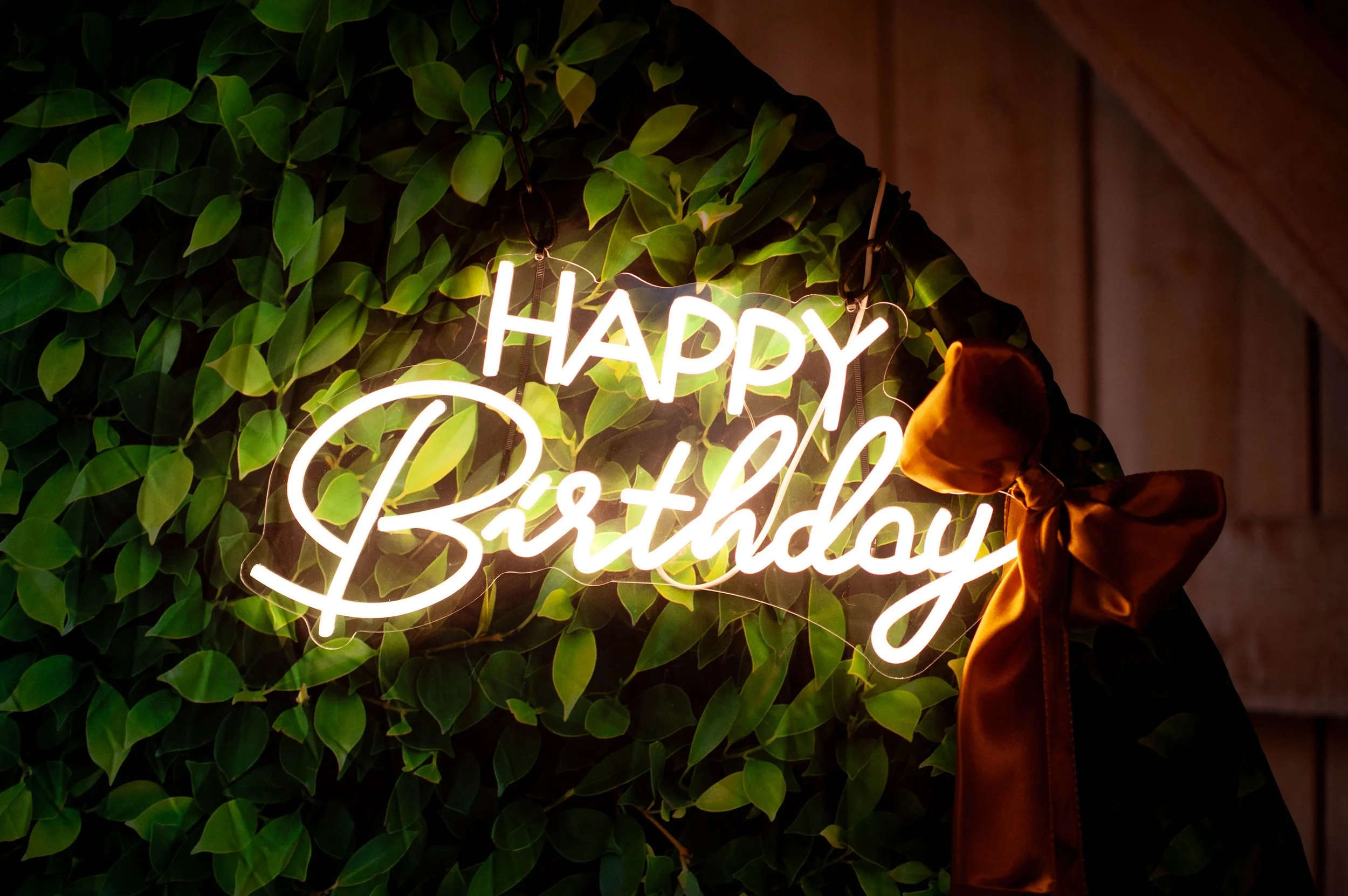 LED Happy Birthday sign with emerald greenery for an elegant 60th birthday celebration.