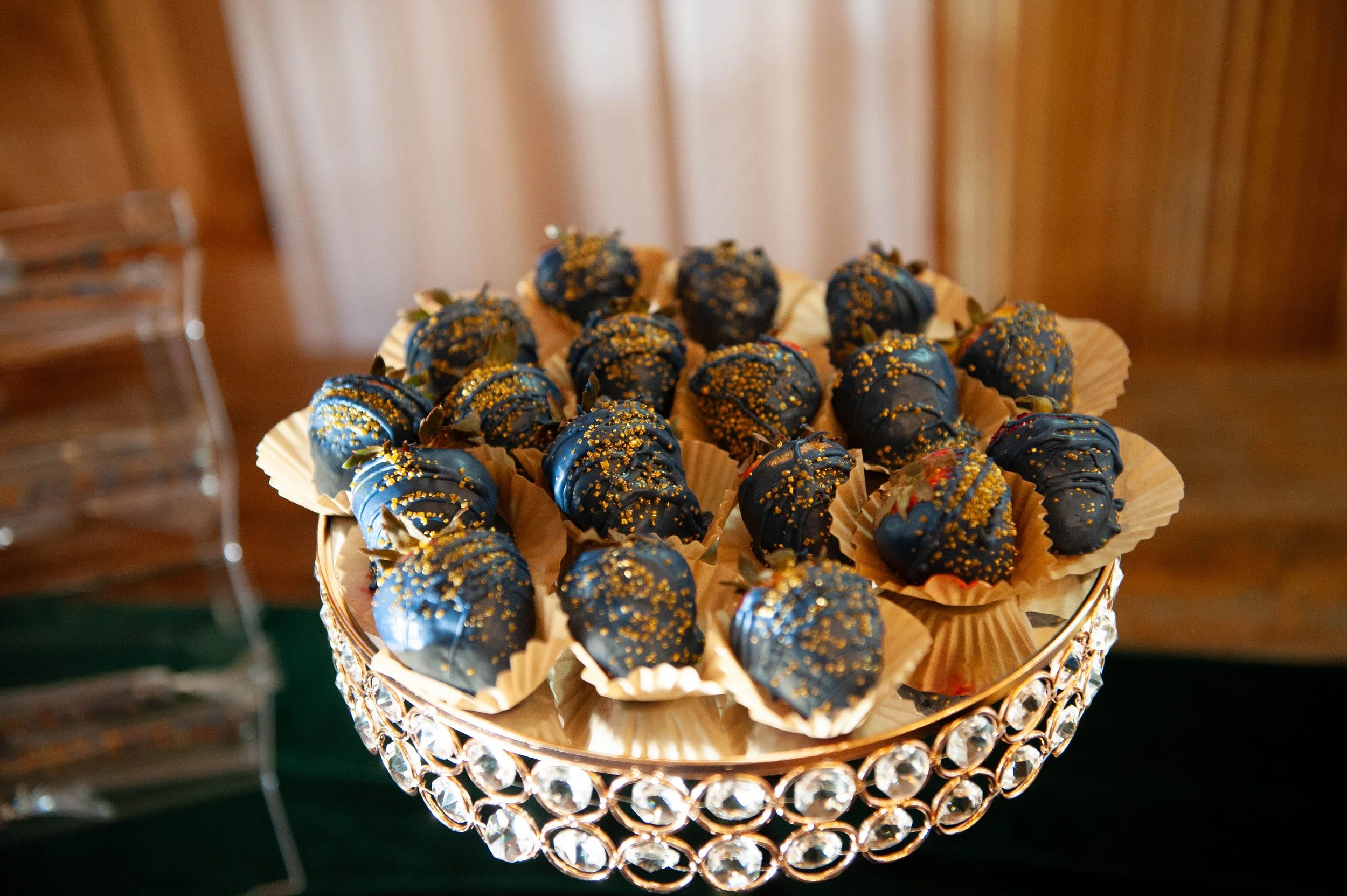 Chocolate-covered strawberries with navy and gold details displayed on an elegant dessert stand.