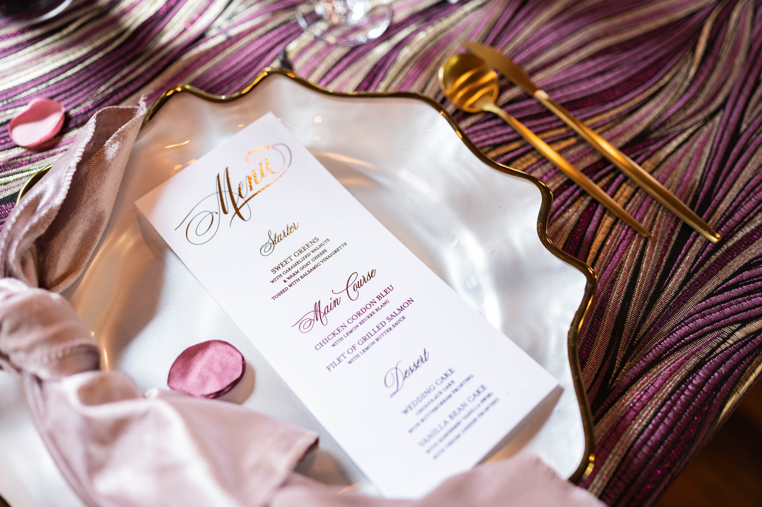Elegant wedding menu with gold details, soft napkin styling and layered place setting.