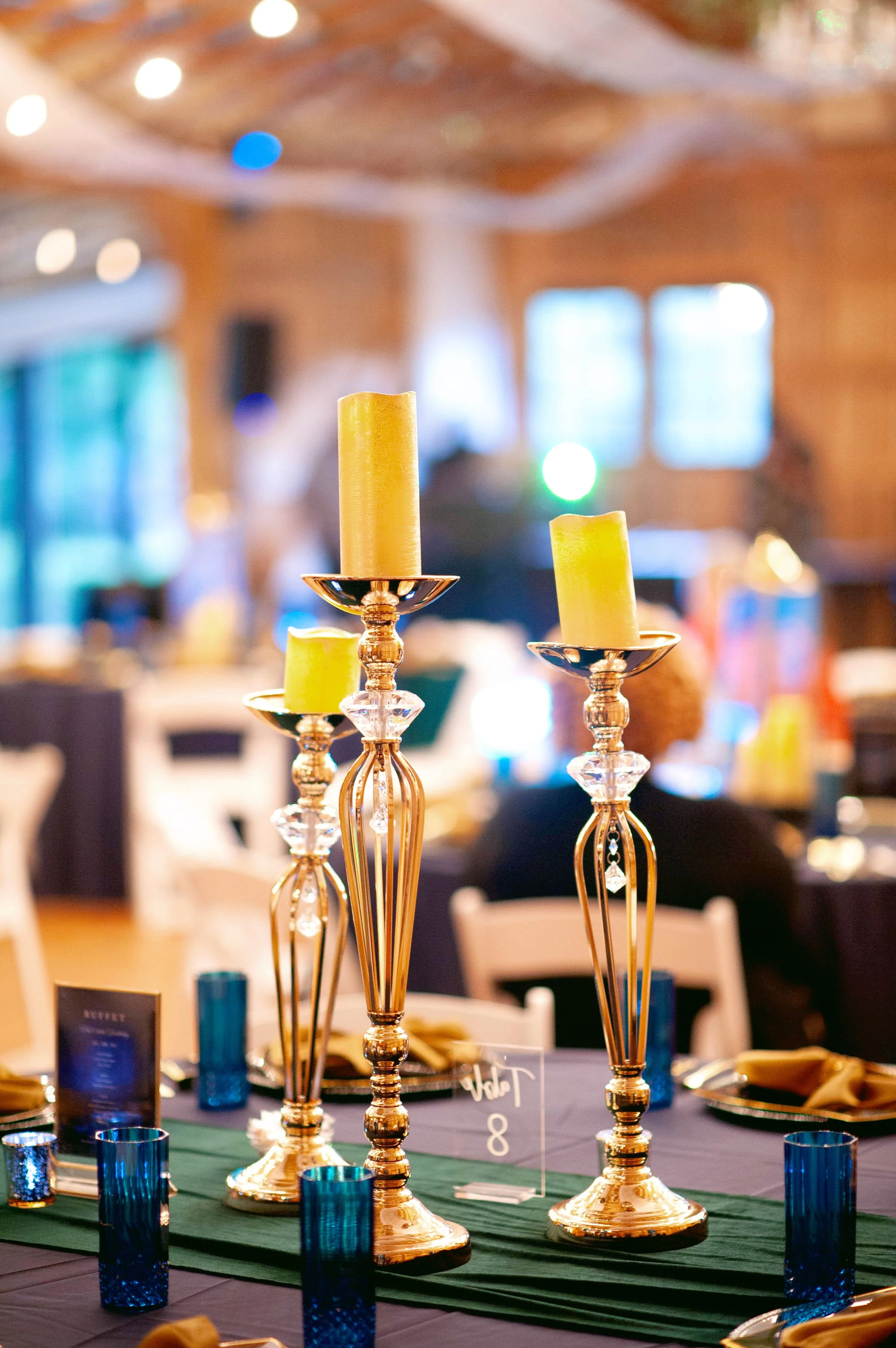 Tall gold candlestick centerpieces with warm candlelight for an elegant 60th birthday tablescape.
