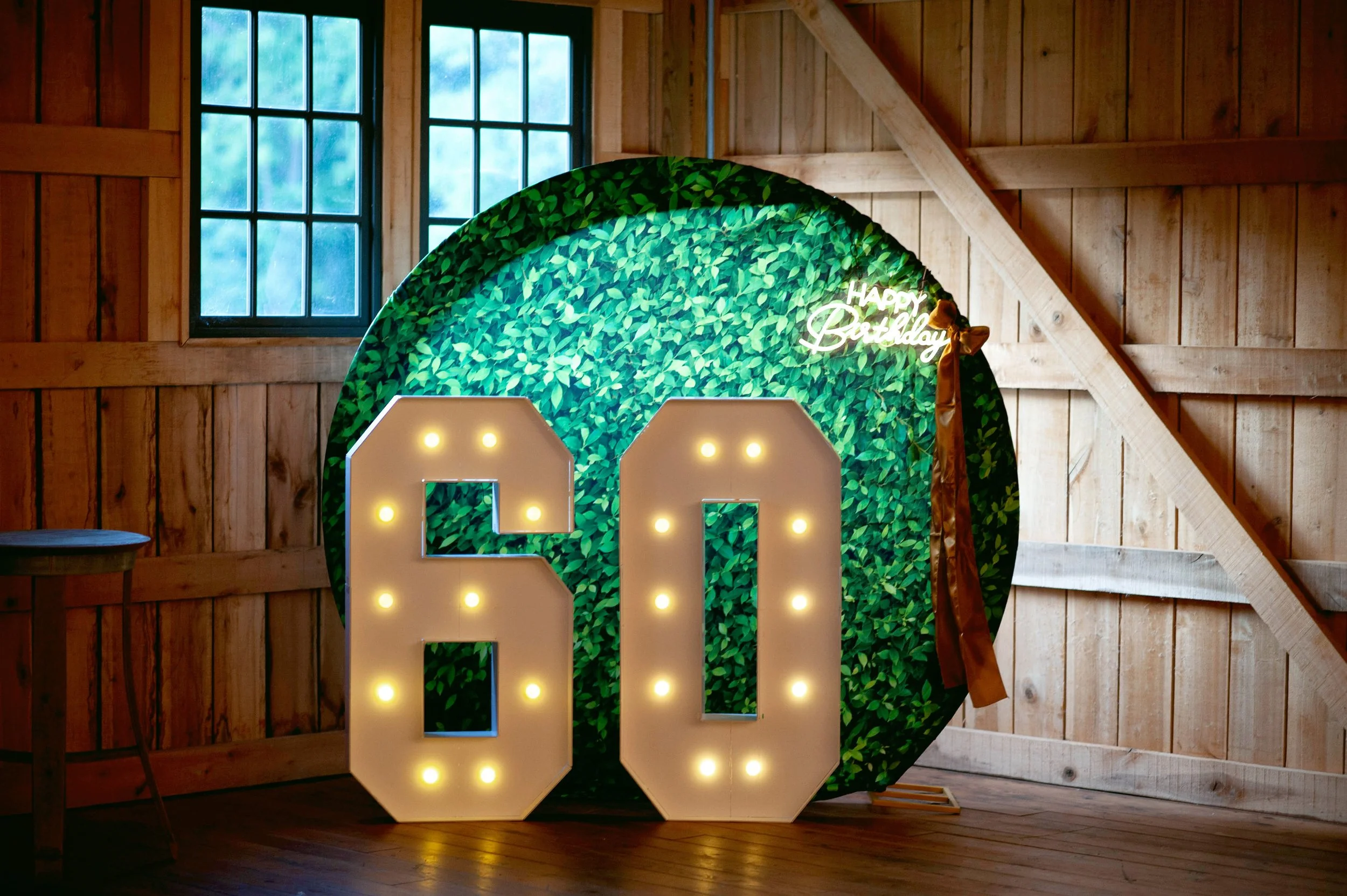 Illuminated 60 marquee numbers with emerald greenery for a milestone birthday celebration.