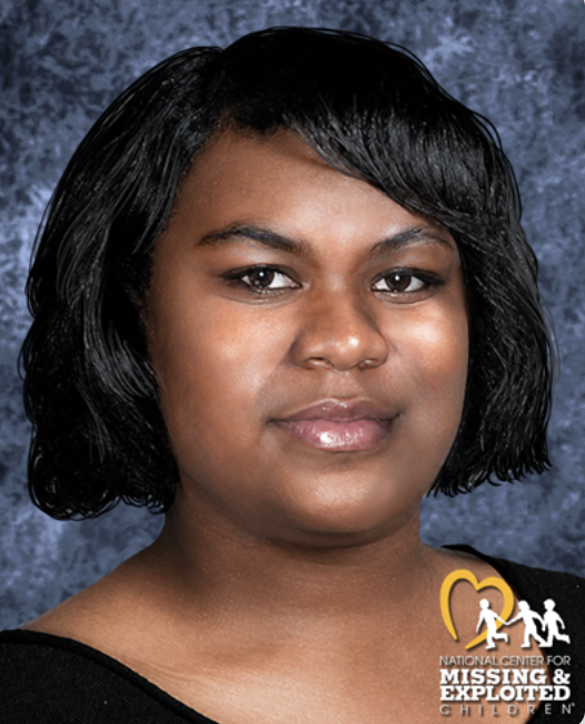 A young African American woman with short black wavy hair, wearing a black top, posing against a dark blue textured background. Logo of the National Center for Missing & Exploited Children is in the bottom right corner.