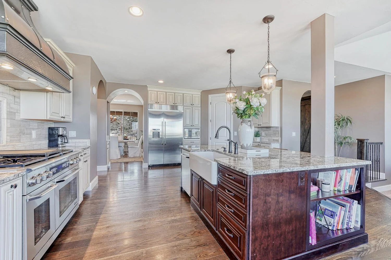 Kitchen featuring a stainless steel range and custom hood, hardwood flooring, refrigerator and an open view into the dining room