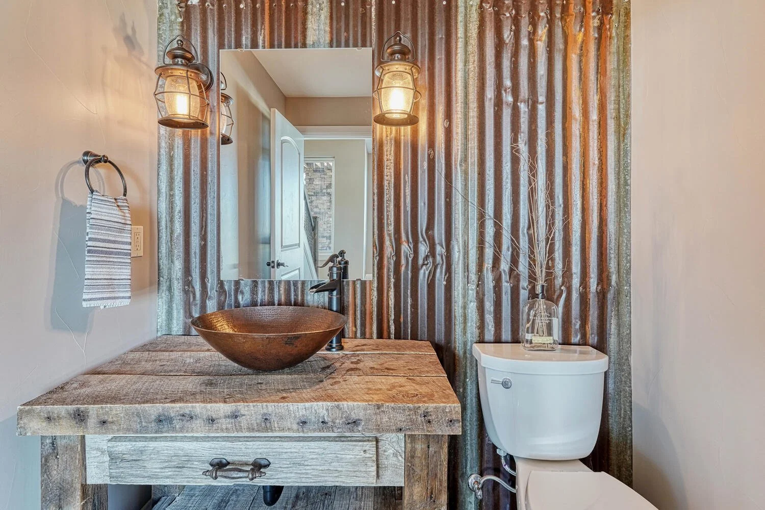 Rustic powder bathroom featuring a reclaimed wood vanity, copper vessel sink, corrugated metal accent wall, and vintage lantern-style lighting