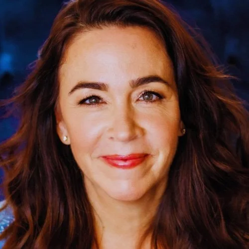 A woman with long, wavy brown hair smiling at the camera.