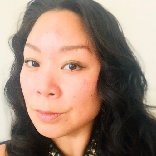 A woman with wavy black hair looking at the camera with a slight smile.