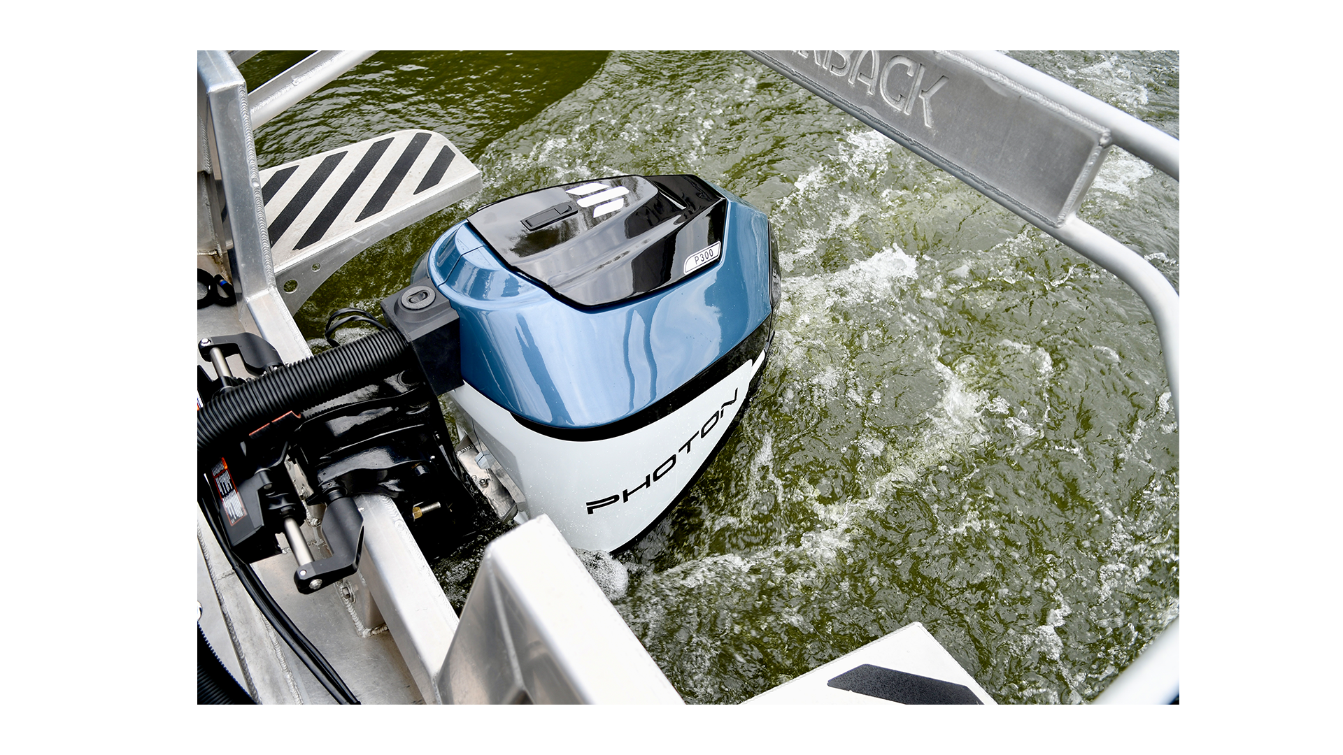 AN electric Outboard motor mounted on to a work boat in the water.