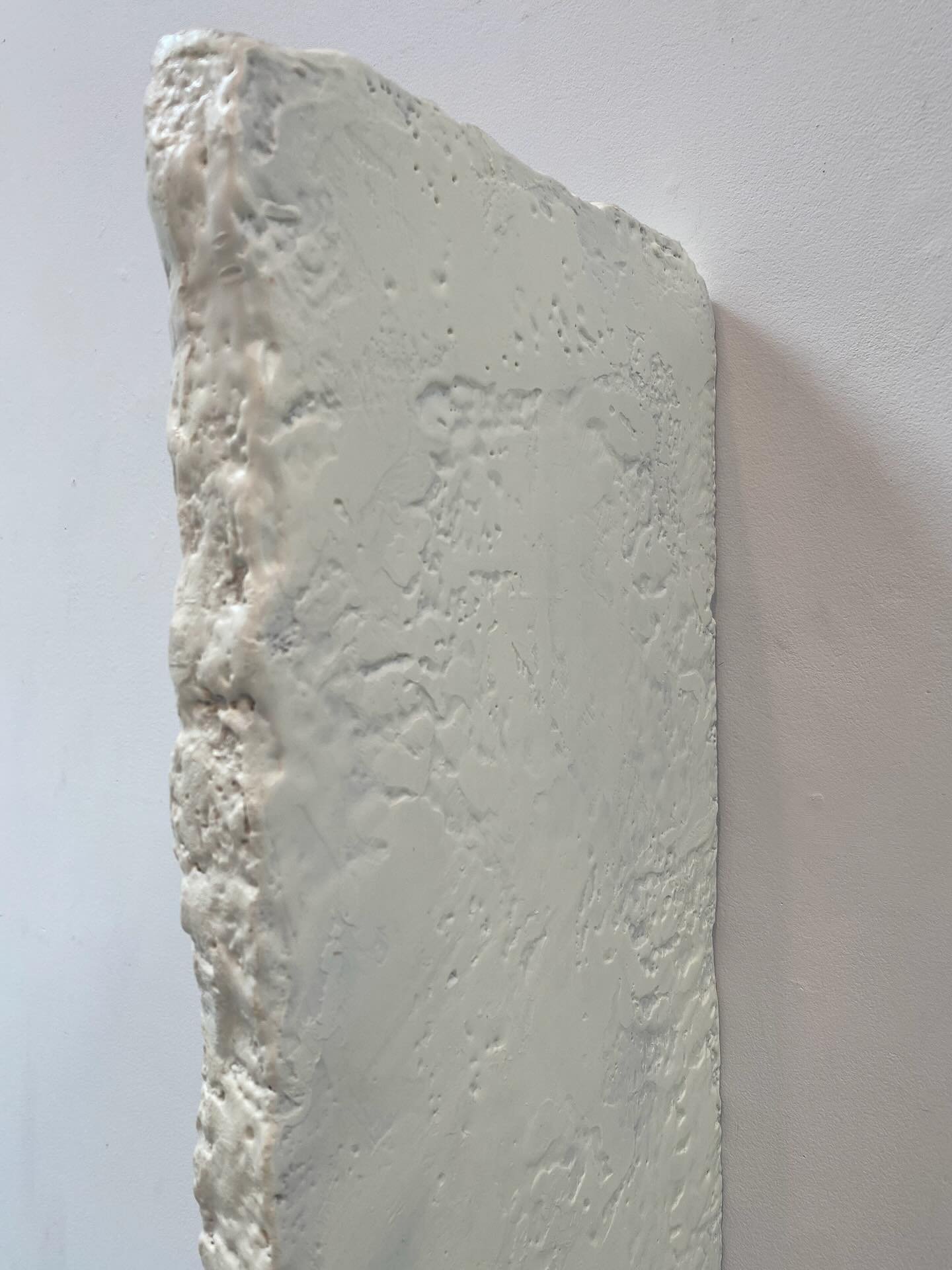 Close-up of a textured white brick wall against a plain white ceiling.