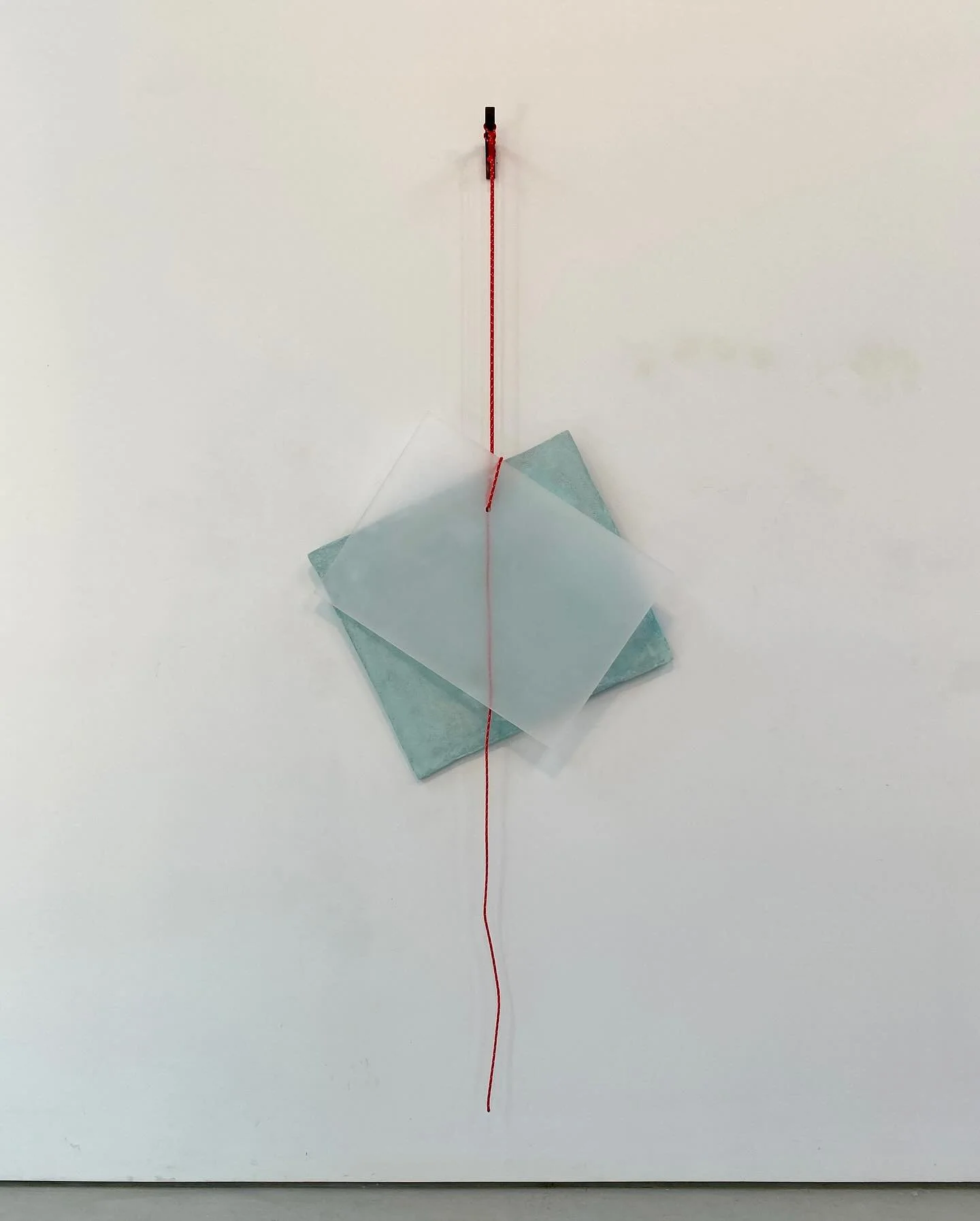 A wall with a hanging star-shaped paper decoration, a red string, and a retractable measuring tape extending downward.