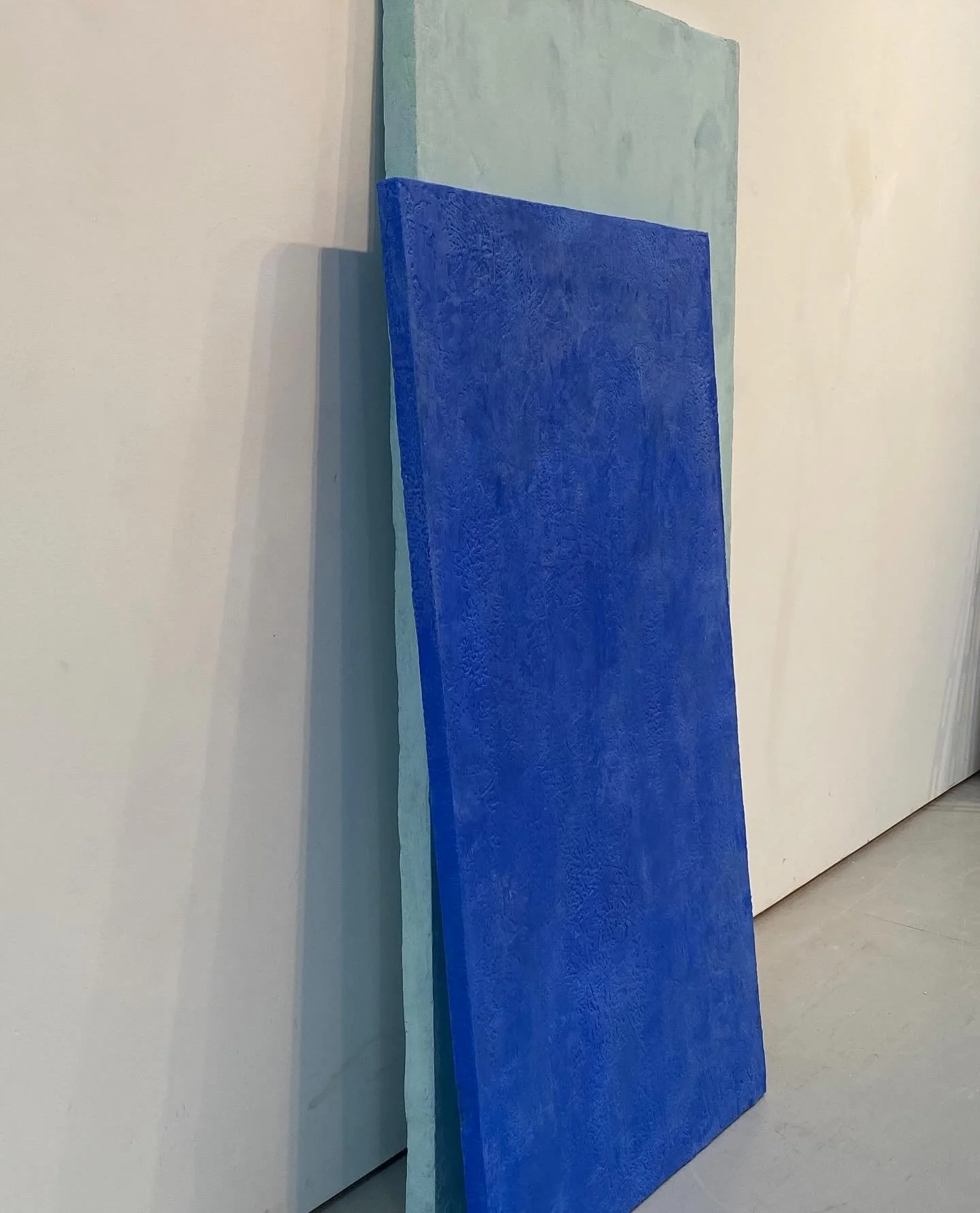 Three colored panels leaning against a white wall.