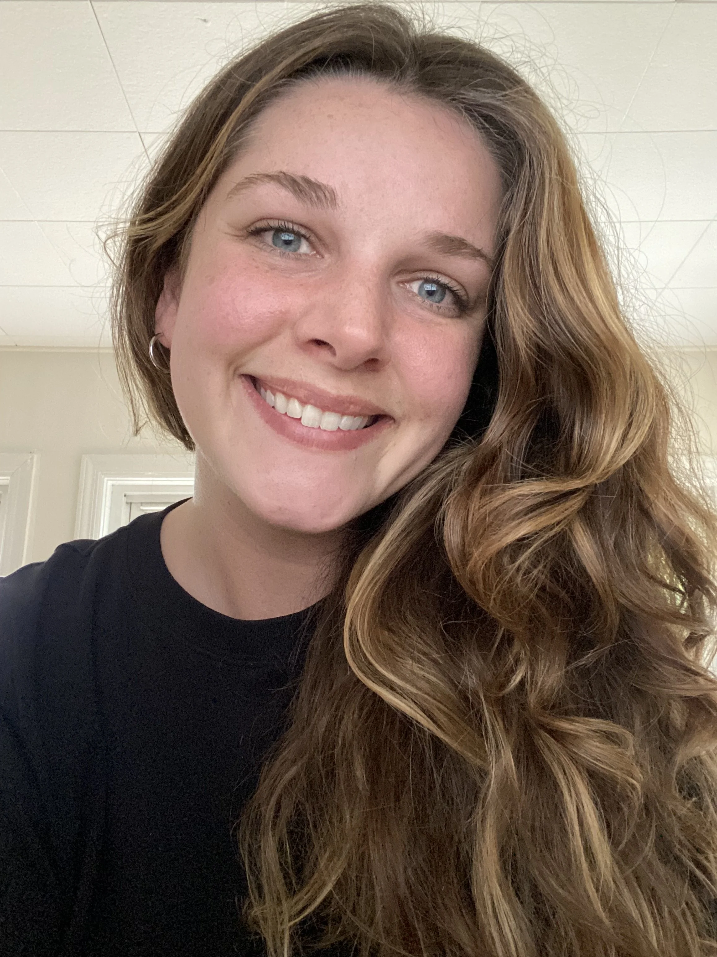 Portrait of Melissa Fraser smiling, with wavy brown hair and a black top.