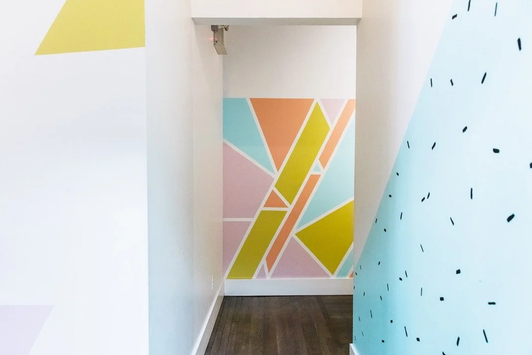 Colorful geometric wall mural with pastel and bright shades, including pink, green, orange, and blue, in a modern interior space.