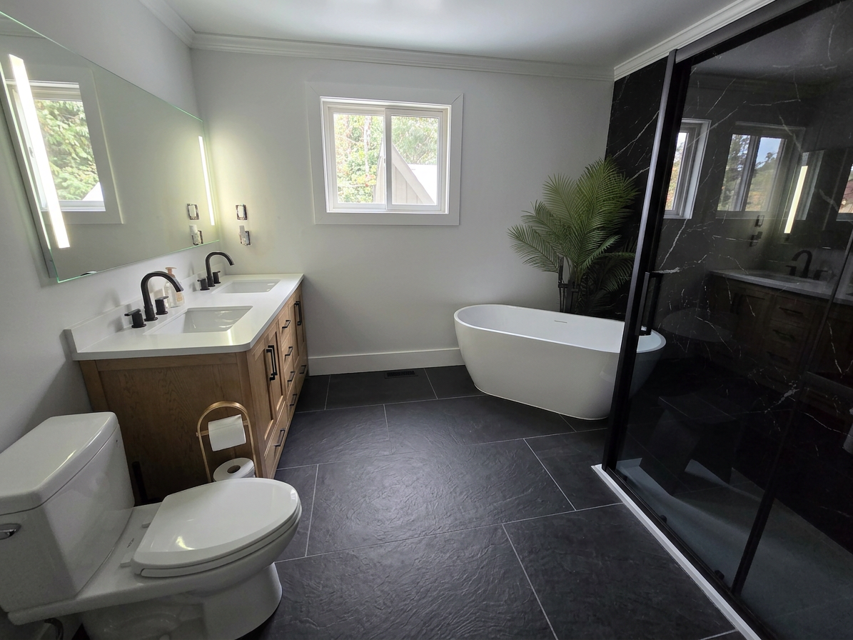 Modern bathroom with a white bathtub, a dual sink vanity with a large mirror, black fixtures, a toilet with a toilet paper holder, a window, and a black marble shower enclosure with sliding glass doors, a towel rack, and a potted plant.
