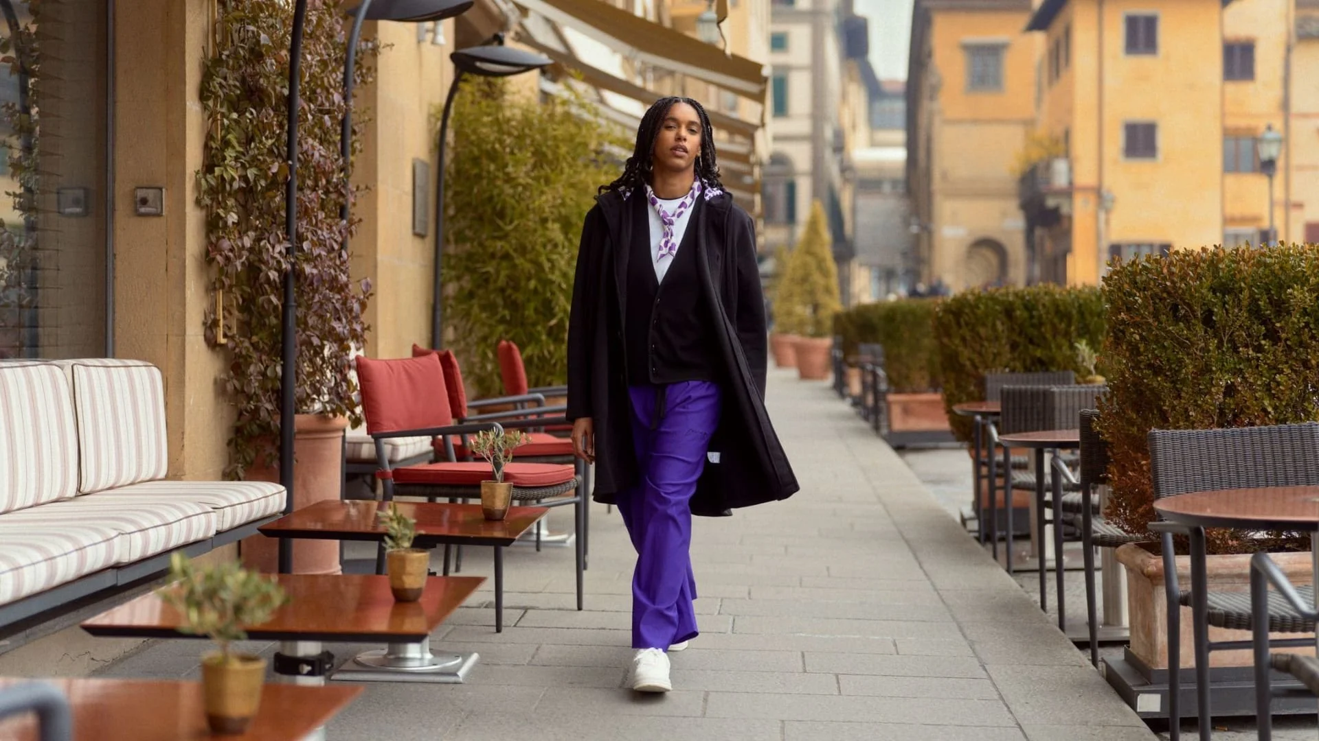 CGT Love You campaign model in purple trousers and dark outerwear on a city terrace