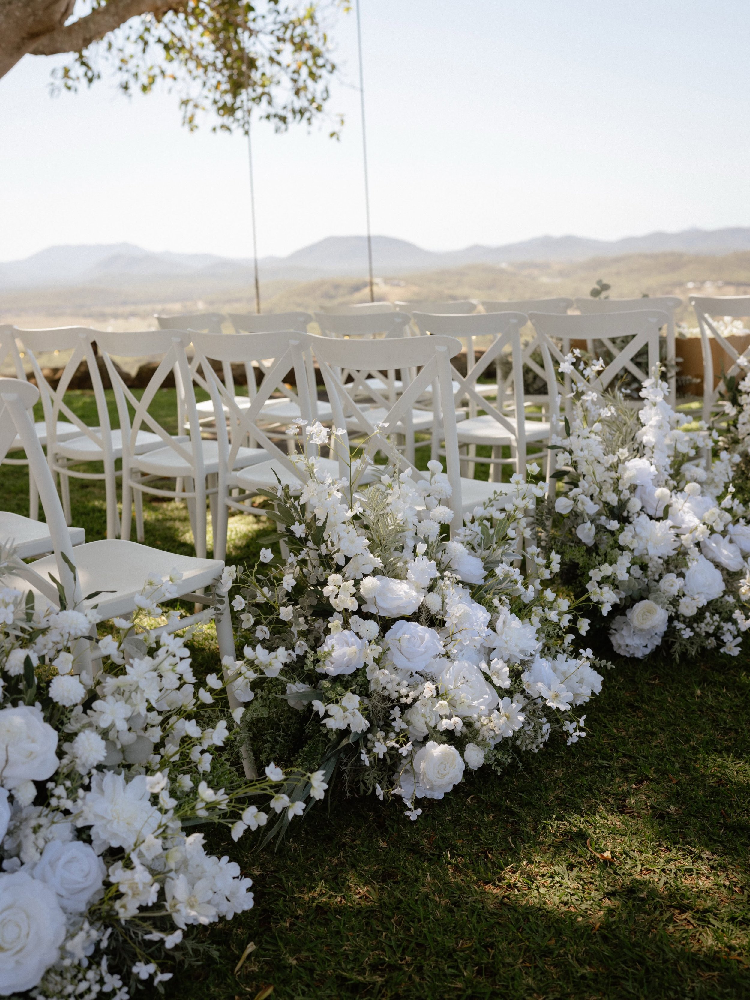 Outdoor wedding ceremony at The Lookout Woodbury on Queensland's Capricorn Coast, with white chairs and floral arrangements overlooking the coastal landscape.